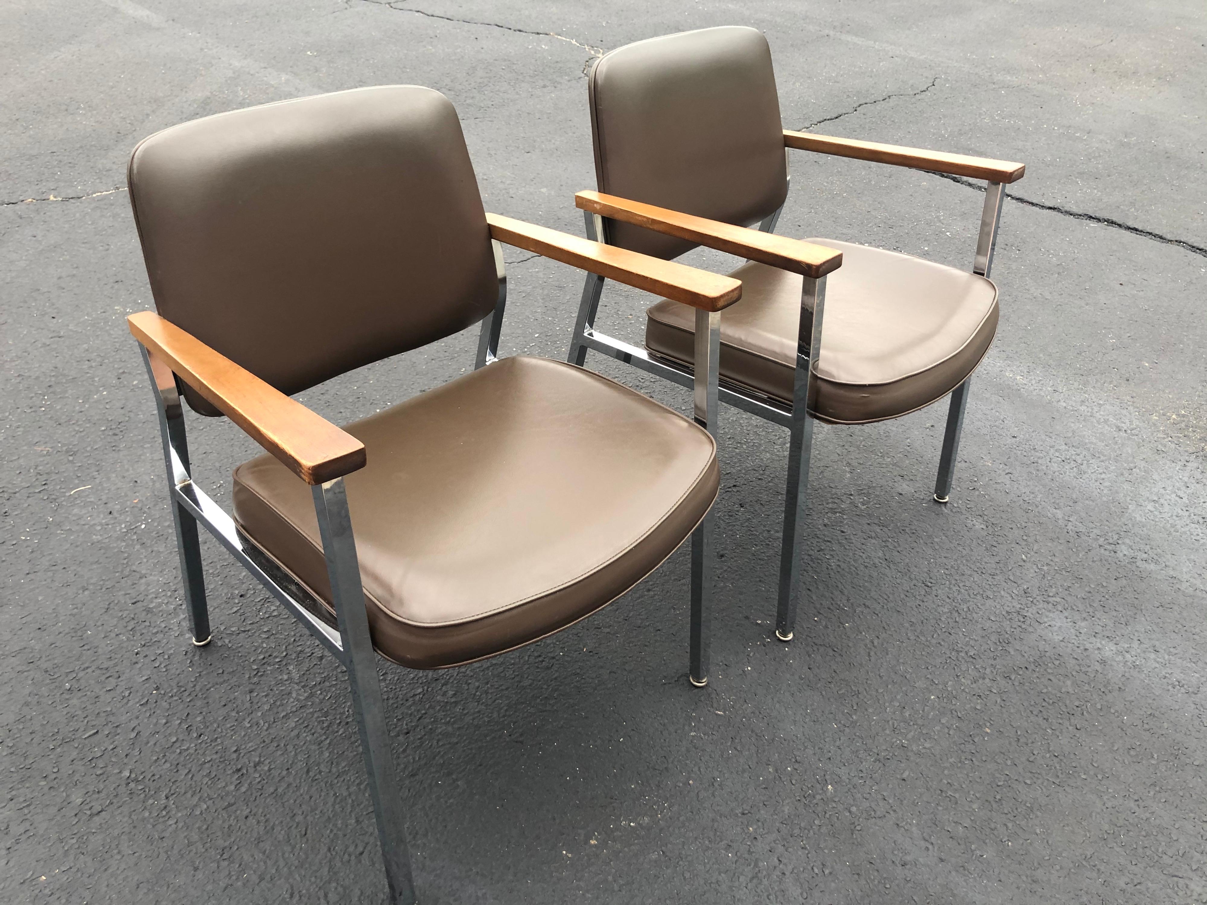 Pair of mid century chrome office chairs in sage brown vinyl. With Classic solid walnut arm rests. These would make a great addition to any home office. Made by United chair company out of Alabama. For you animal lovers this is vegan leather-vinyl.