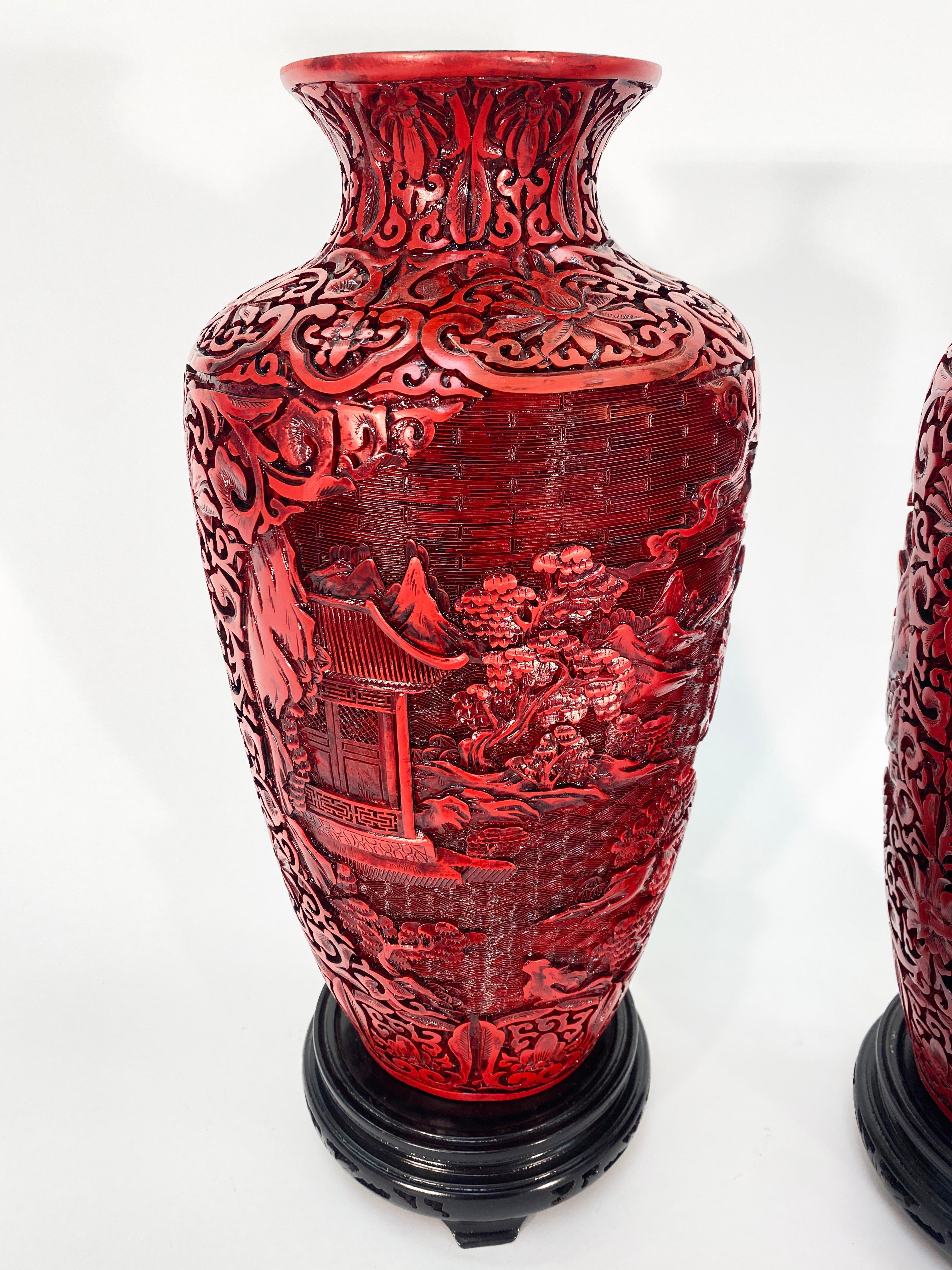 Gorgeous pair of midcentury cinnabar hand carved vases. Highly detailed carvings in the red lacquer. Paired with rosewood vase stands. 

Asian 20th century 

Measure: Height 17”
Width 7”.