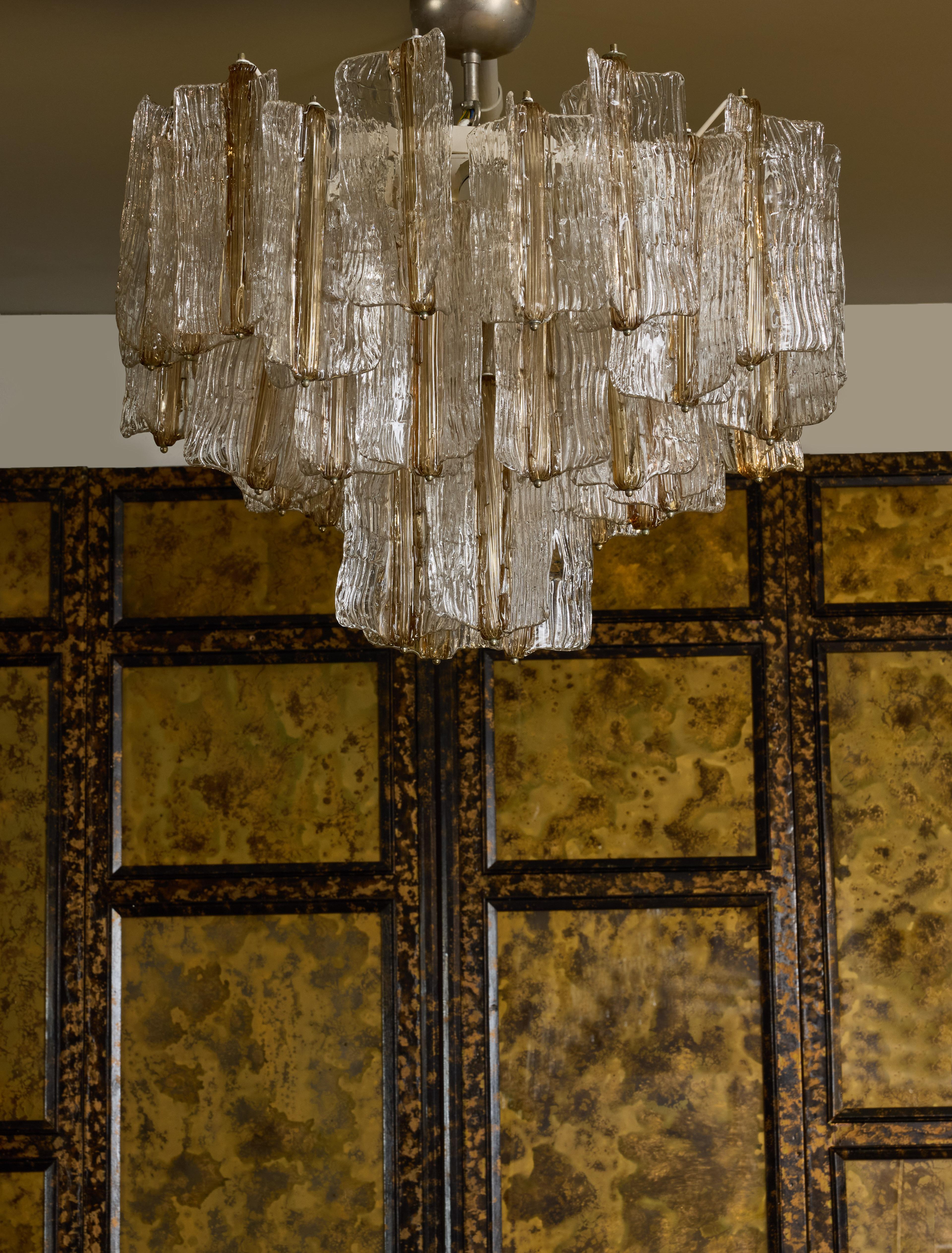 Pair of chandelier made of a painted metal structure holding height sources of light, from which hang Murano glass large tassels.

Each tassel is clear textured Murano glass, three panels merging in their center with the center in smoked colour.