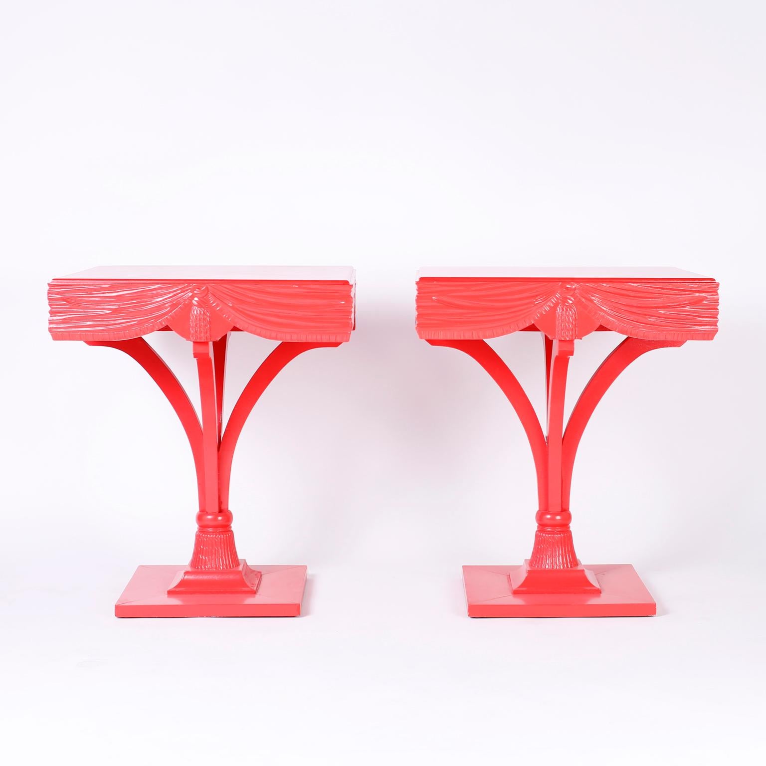 Dramatic pair of midcentury Regency style end tables lacquered in a striking coral color with square tops, carved wood drape and tassel skirts, stylized blume legs connected with a tassel on a double plinth square base.