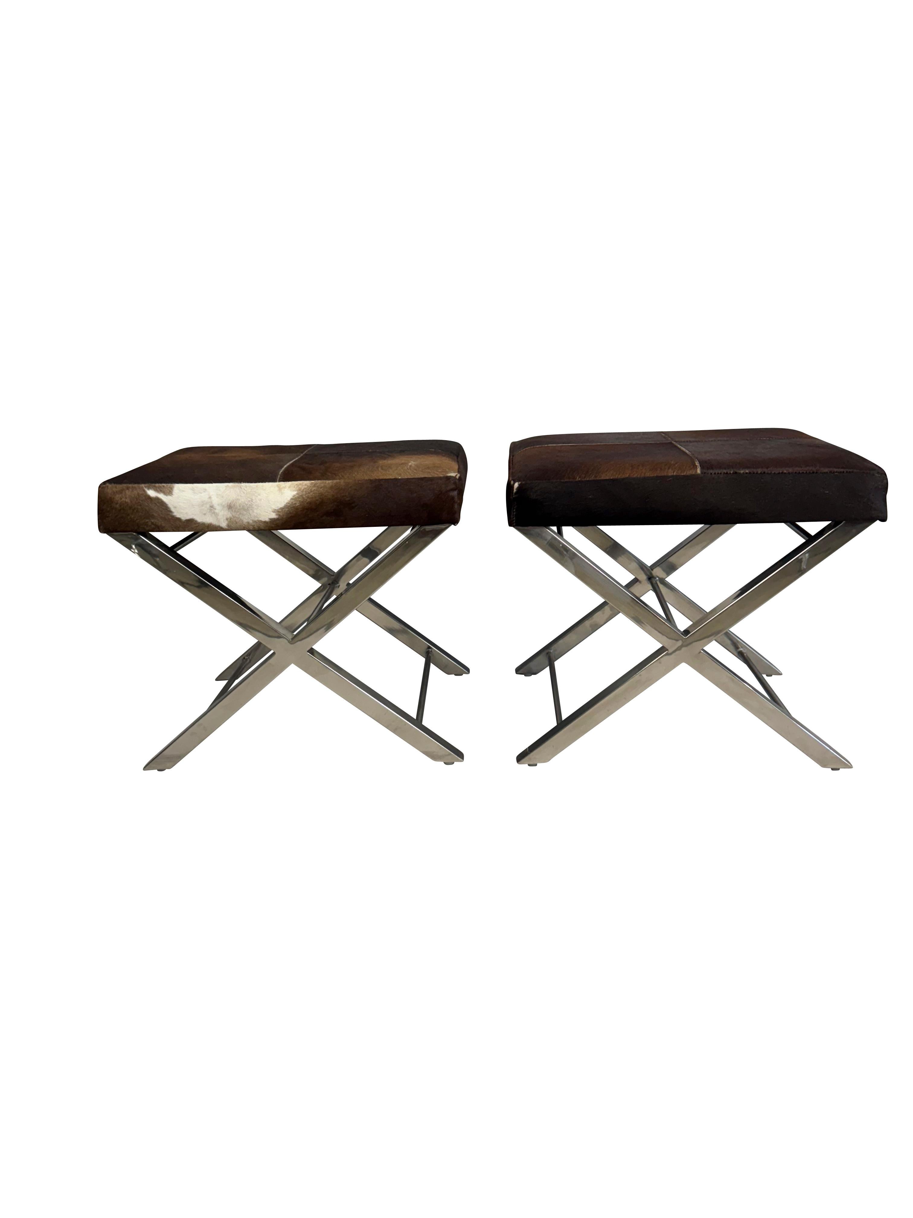 Coppia di panche di metà secolo rivestite in pelle di mucca con basi a croce cromate.  Pelle bovina naturale di colore marrone e bianco con sfumature tan.  Bella base cromata lucida a gambe incrociate.  