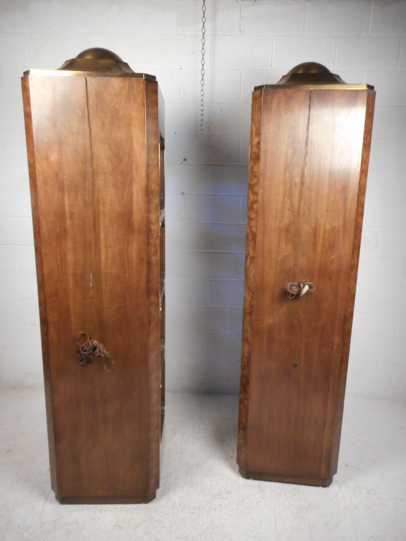 Impressive pair of midcentury curios/display cabinets by Mastercraft. Beautiful burl walnut throughout with brass accents and pulls. Ample storage/display space within. Functional display lights within the top of the cases illuminate the contents of