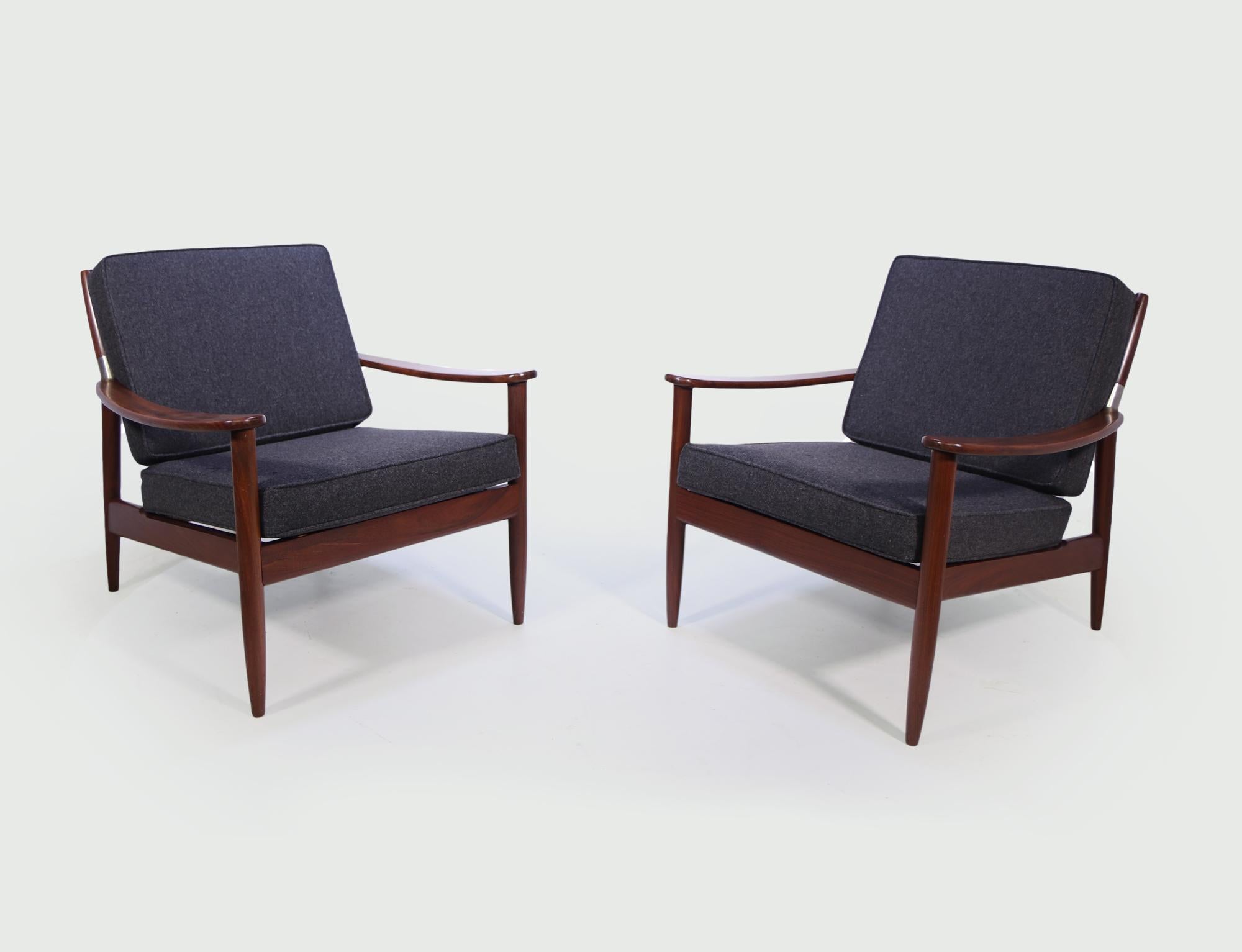 A pair of Danish mid century chairs in solid teak with a polished metal joint where the arm and backrest meet, the frames are good and solid and have had new cushions that have been covered in wool felt fabric in charcoal grey

Age: 1960

Style: