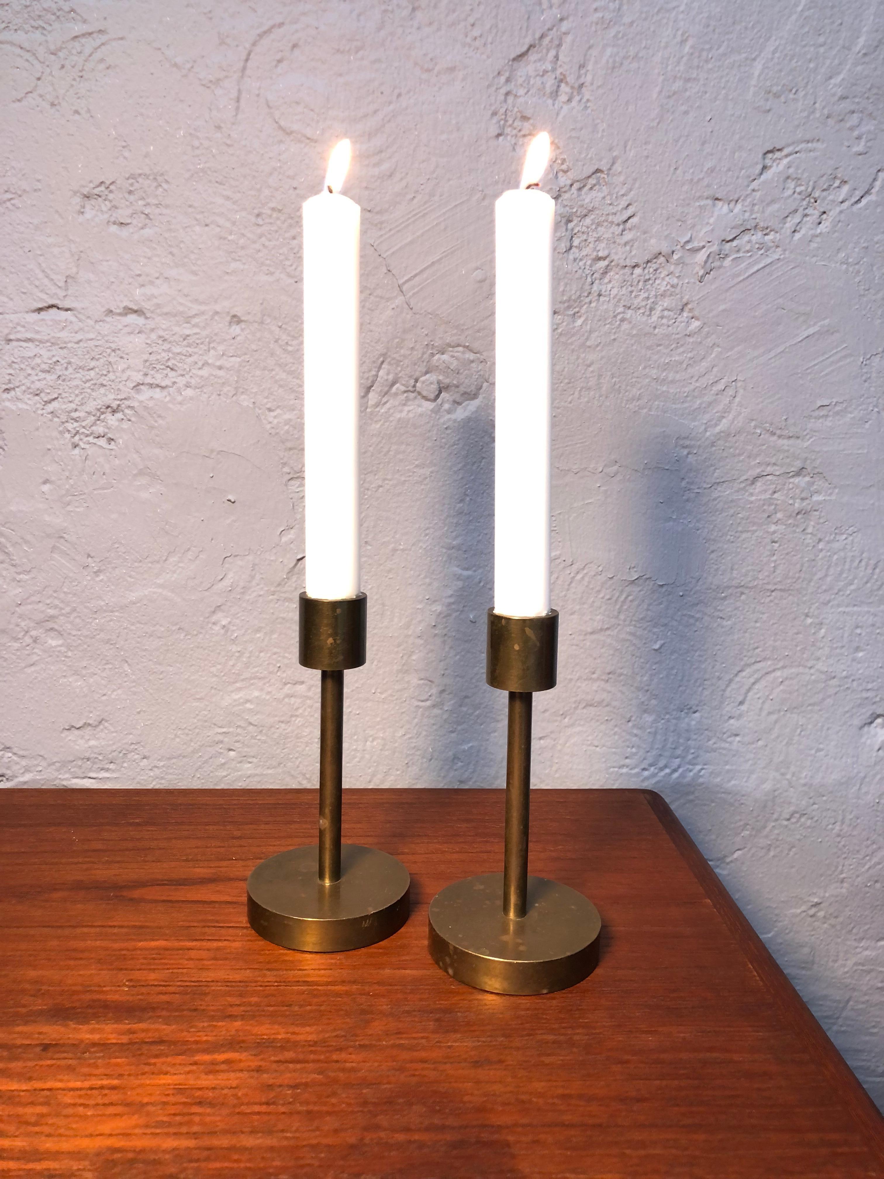A mid-century pair of solid brass candle holders. 
Designer unknown but in the manner of Ilse D. Ammonsen. 
Lovely simplistic period design.
In unpolished condition with age related wear and patina. 
Can be polished if so desired. 
Responsible