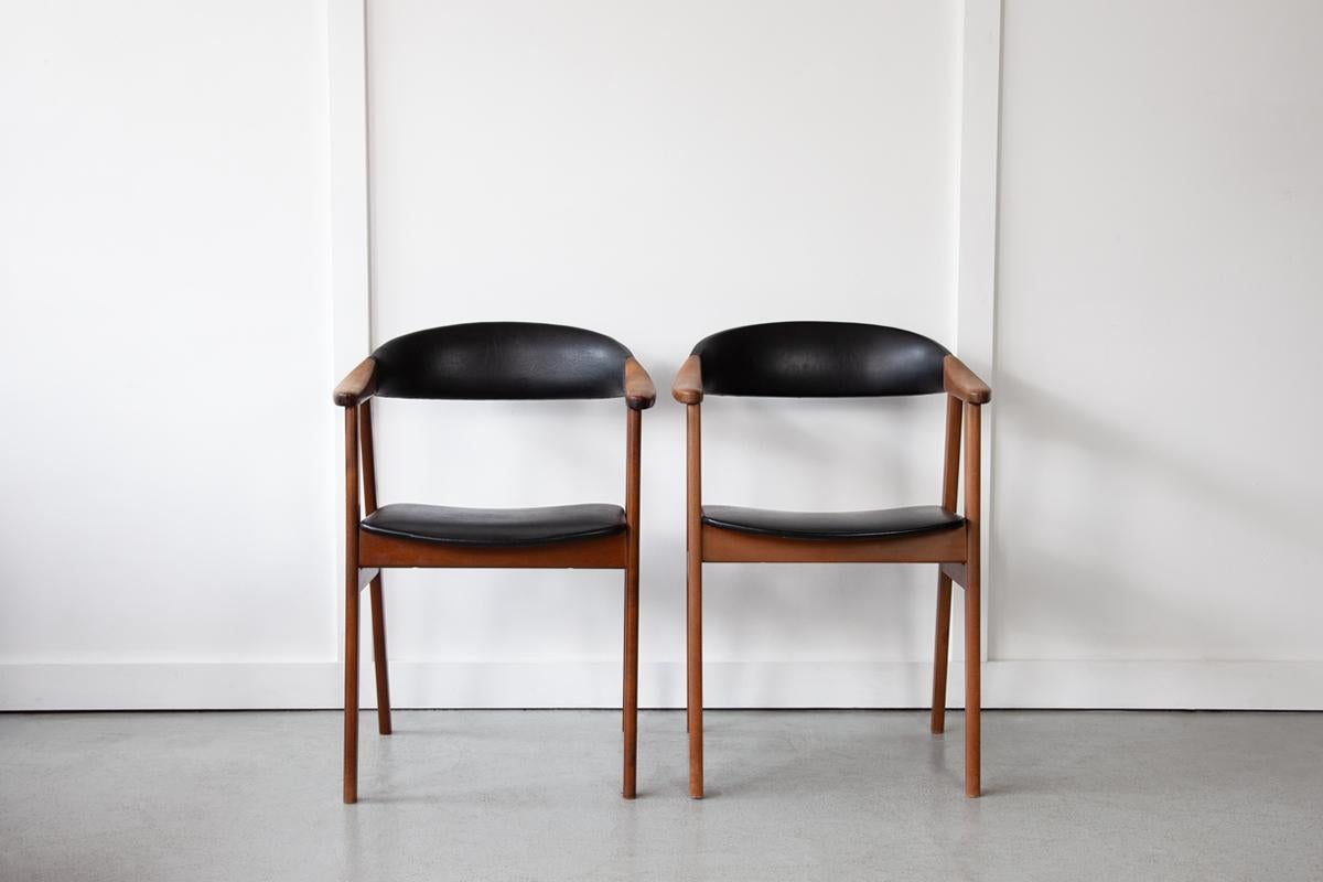 A pair of sweet Danish carver chairs with dynamic, solid oak frames and pleasingly curved back-rests. The chairs are upholstered in their original black skai leather which is in good, vintage condition with no flaws. 
Please note, one chair's frame