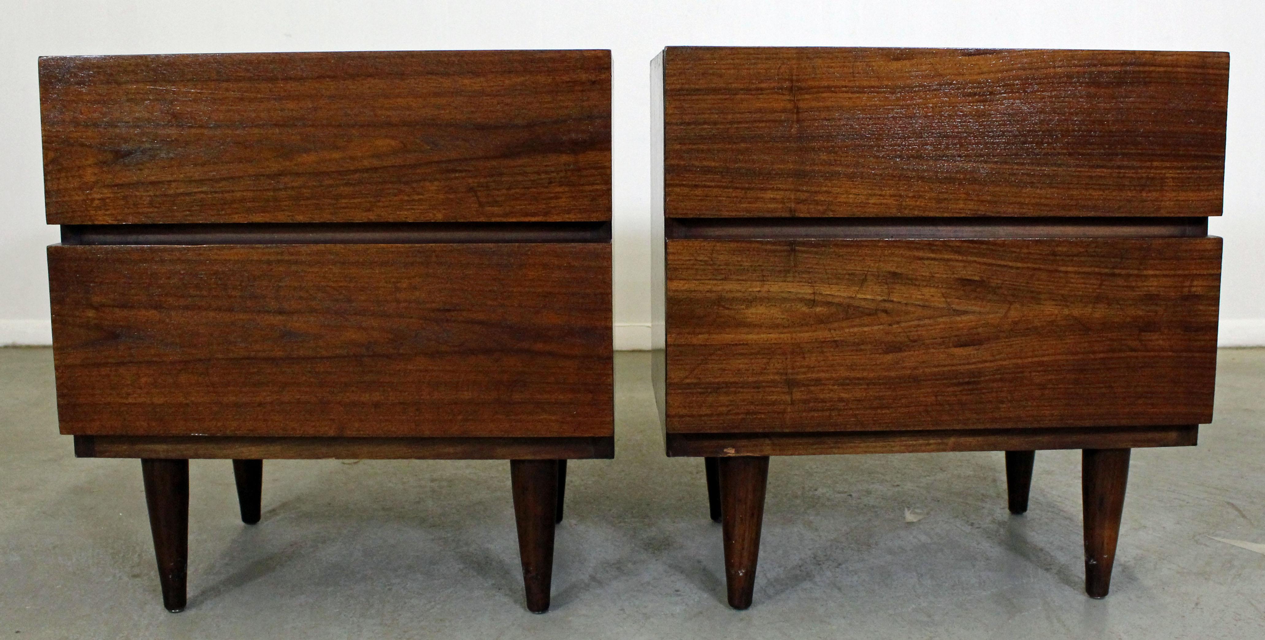Offered is a pair of walnut nightstands made by American of Martinsville. Feature two drawers with hidden pulls. They are in good condition; tops and sides have been refinished. They are signed by American of Martinsville.

Dimensions:
22