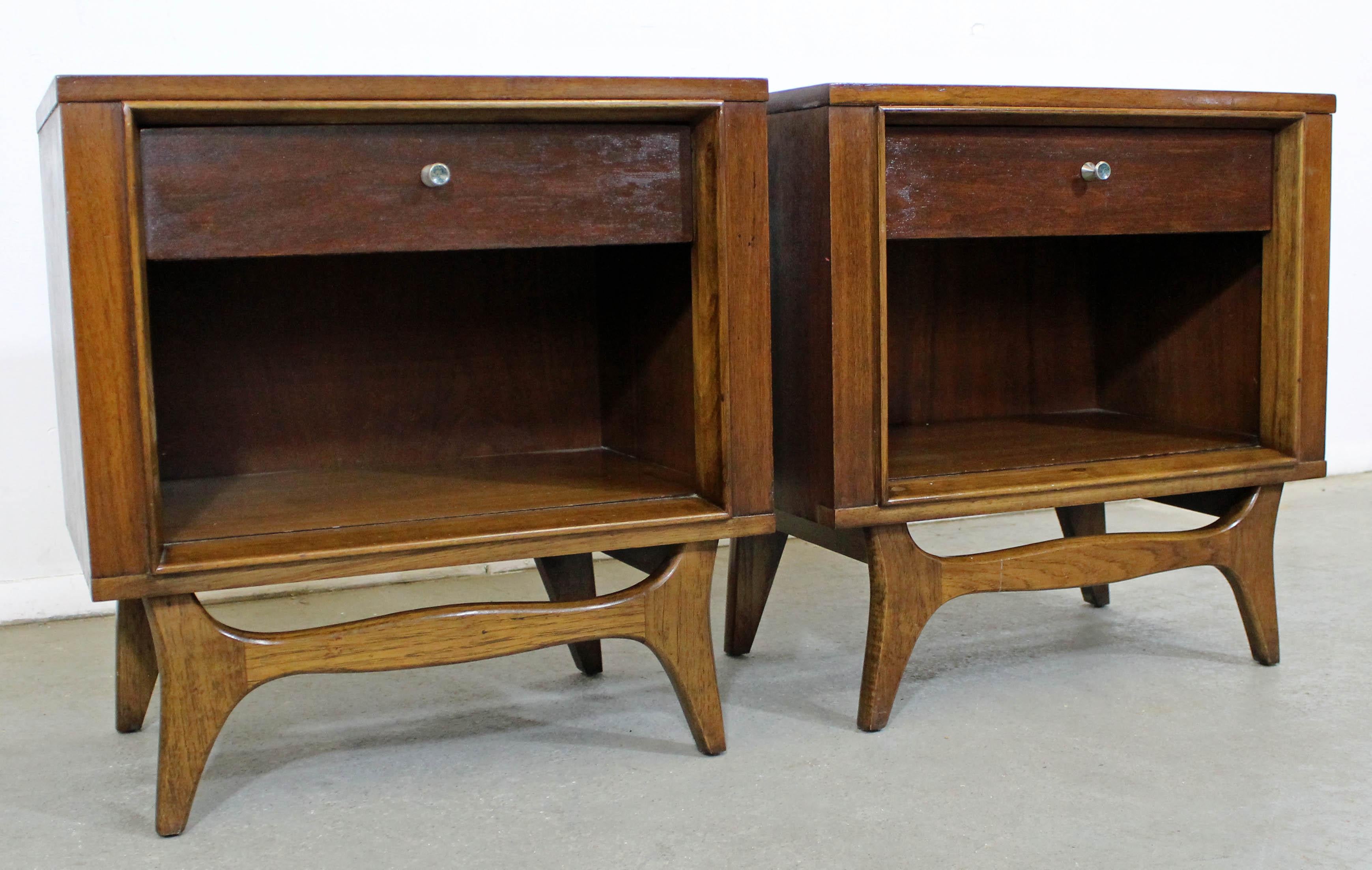 Offered is a pair of Mid-Century Modern nightstands by Kent Coffey's 'Insignia' line. This set is made of walnut, with each featuring one dove-tailed drawer and open storage cabinet. They are in good condition, with refinished tops and sides and