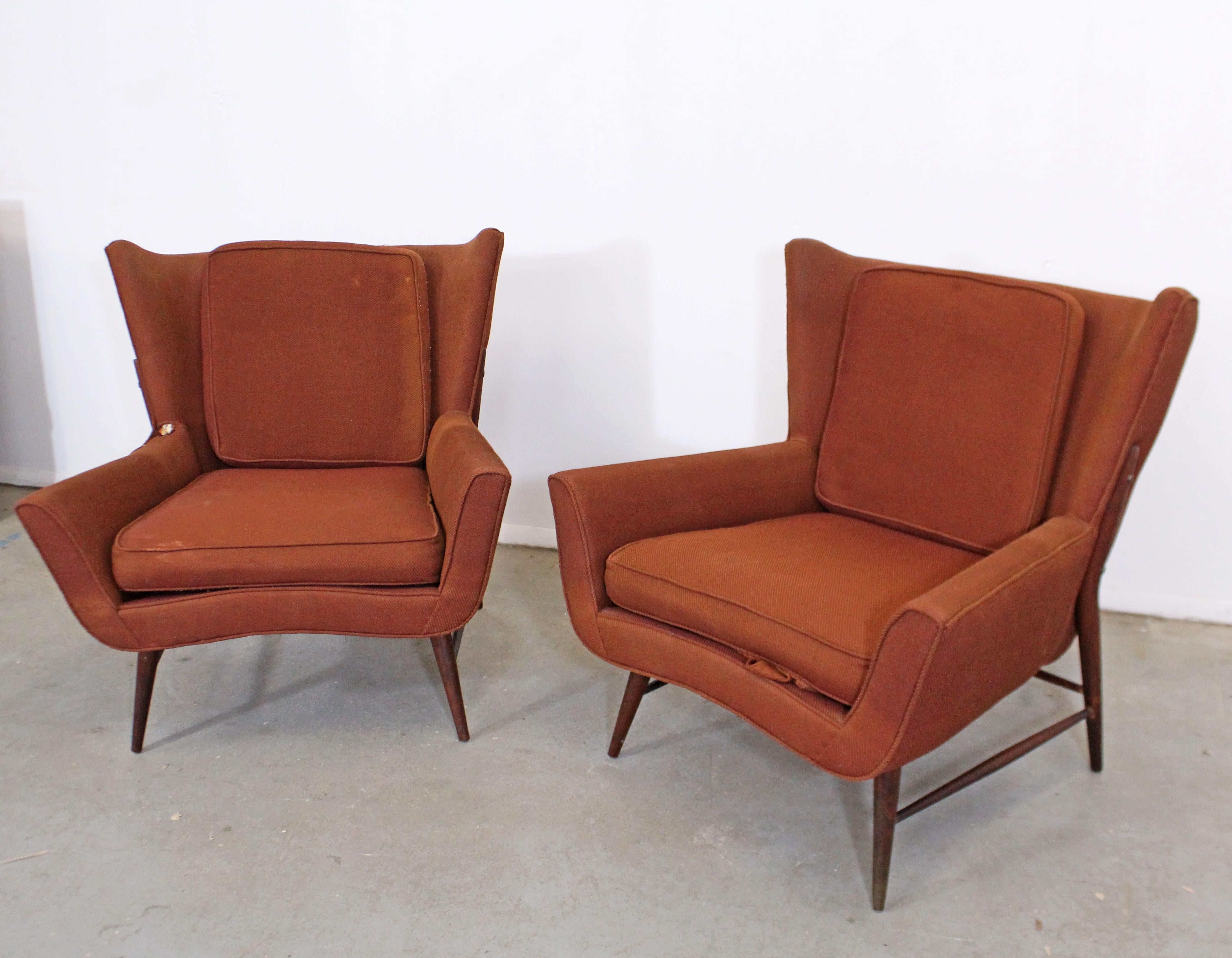 Offered is a pair of vintage mid century wing back lounge chairs. Absolutely incredible lines on these chairs. Featuring a unique shape, with high pencil legs and stretchers, these chairs perfect for any space or design project. Make them your own!