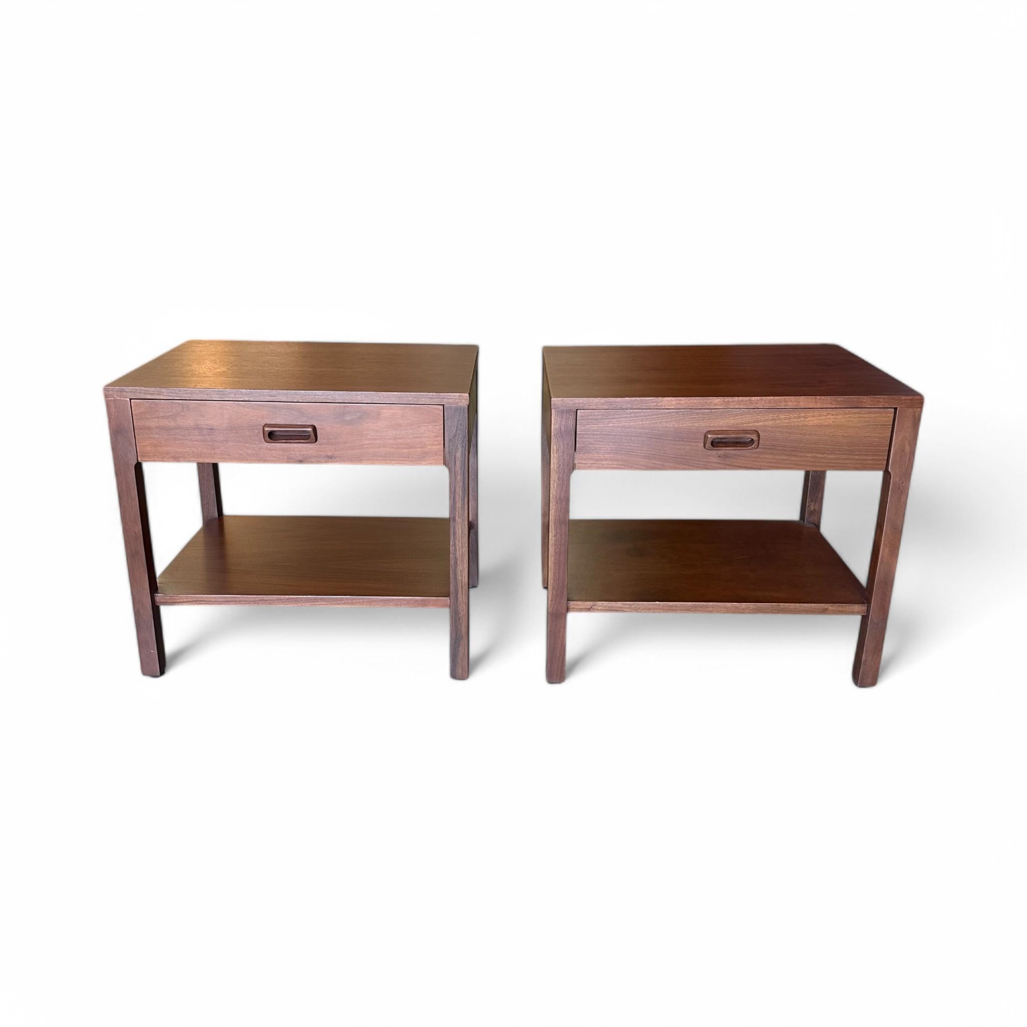 A sleek pair of Mid-Century Danish nightstands, crafted from rich wood with clean lines and timeless appeal. Each features a single drawer with a recessed pull and an open lower shelf for added storage and display. Perfect for bringing understated