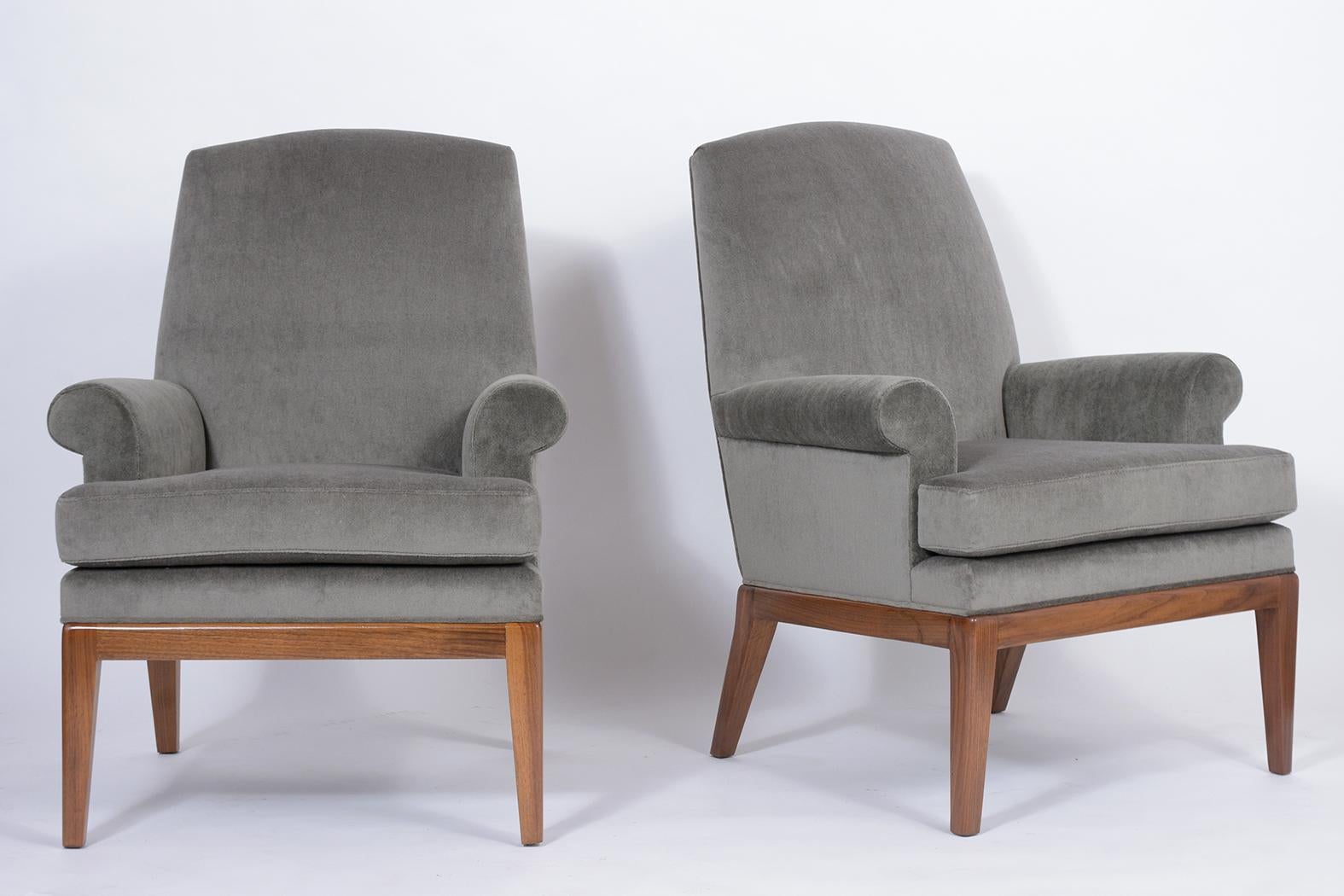 A 1960s pair of Danish style modern lounge chairs handcrafted out of walnut wood with a newly stained in walnut color with a lacquered finish and are professionally restored. These armchairs feature sculpted slatted backrests, rounded armrests, and