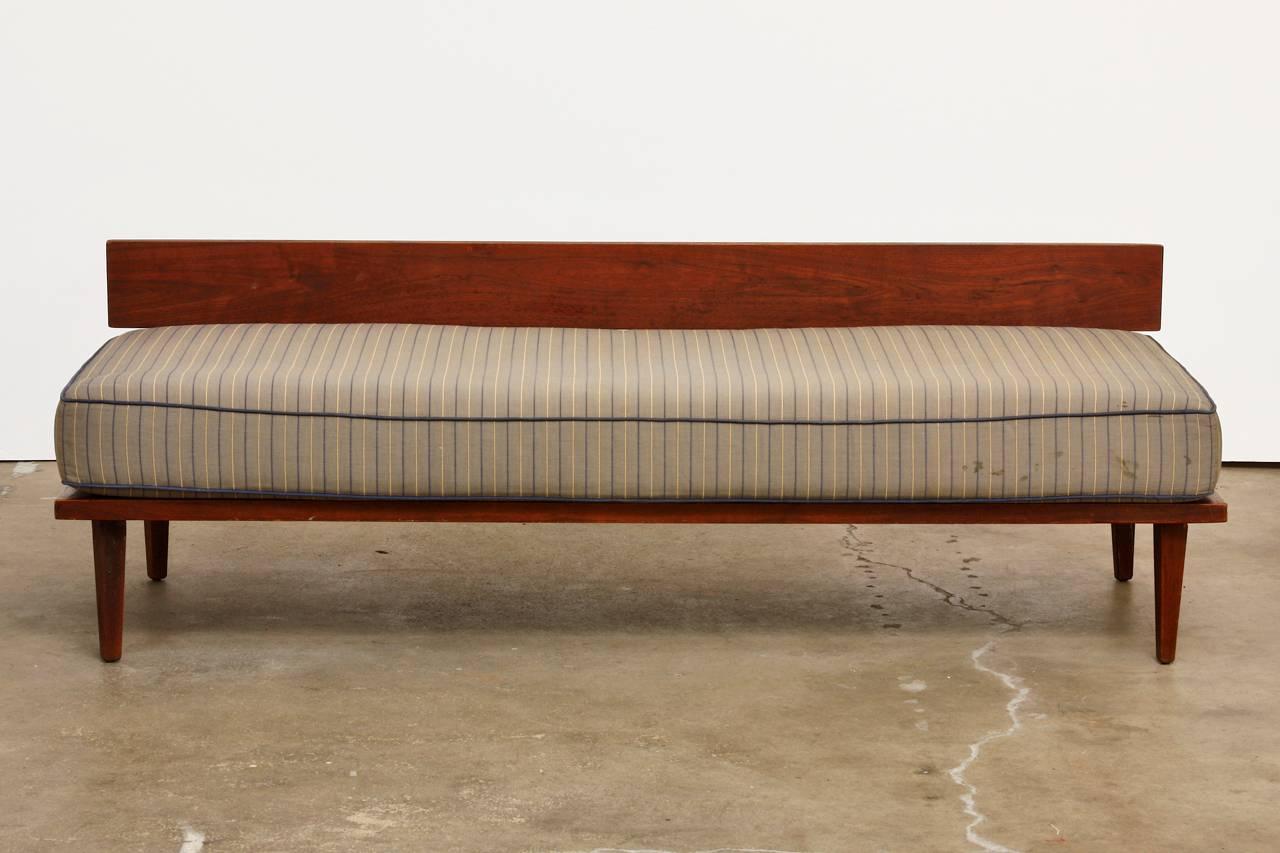 Interesting pair of Mid-Century Modern wooden daybeds with whimsical wedge shaped back cushions. Features a wood plank backrest supported by iron straps. Each frame has a seat height of 11