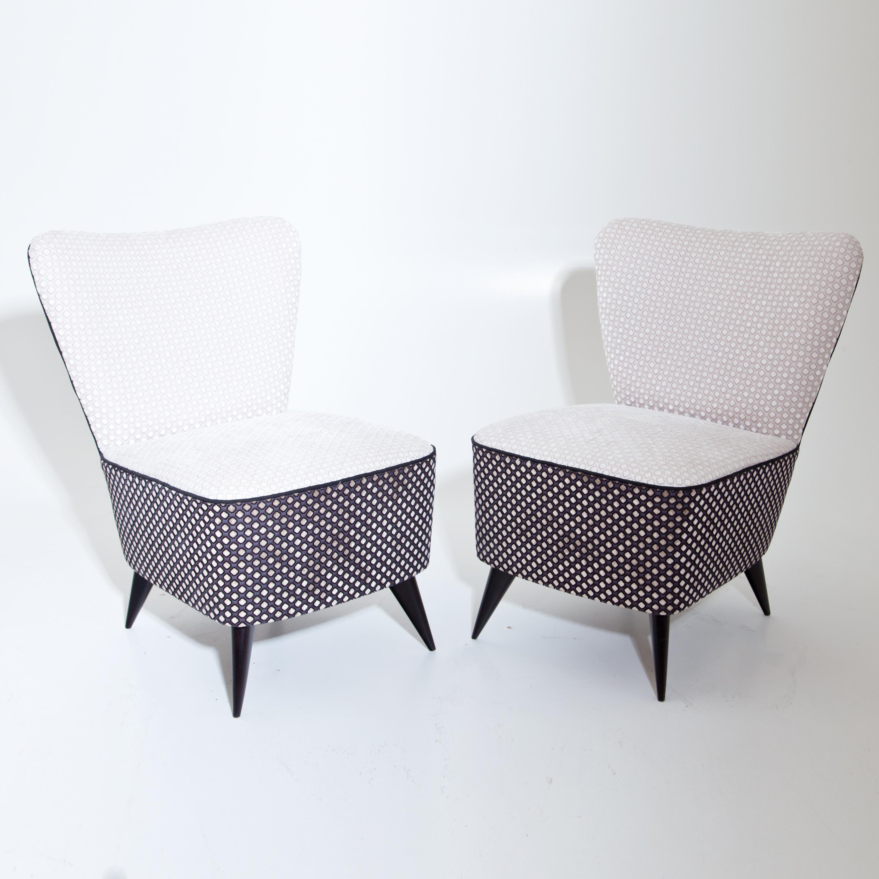 Pair of slipper chairs on black conical legs with trapezoidal backrests and thickly upholstered seats. The armchairs have been newly covered with a high-quality fabric in beige or dark blue with textured rhombus patterns and black piping.
 
