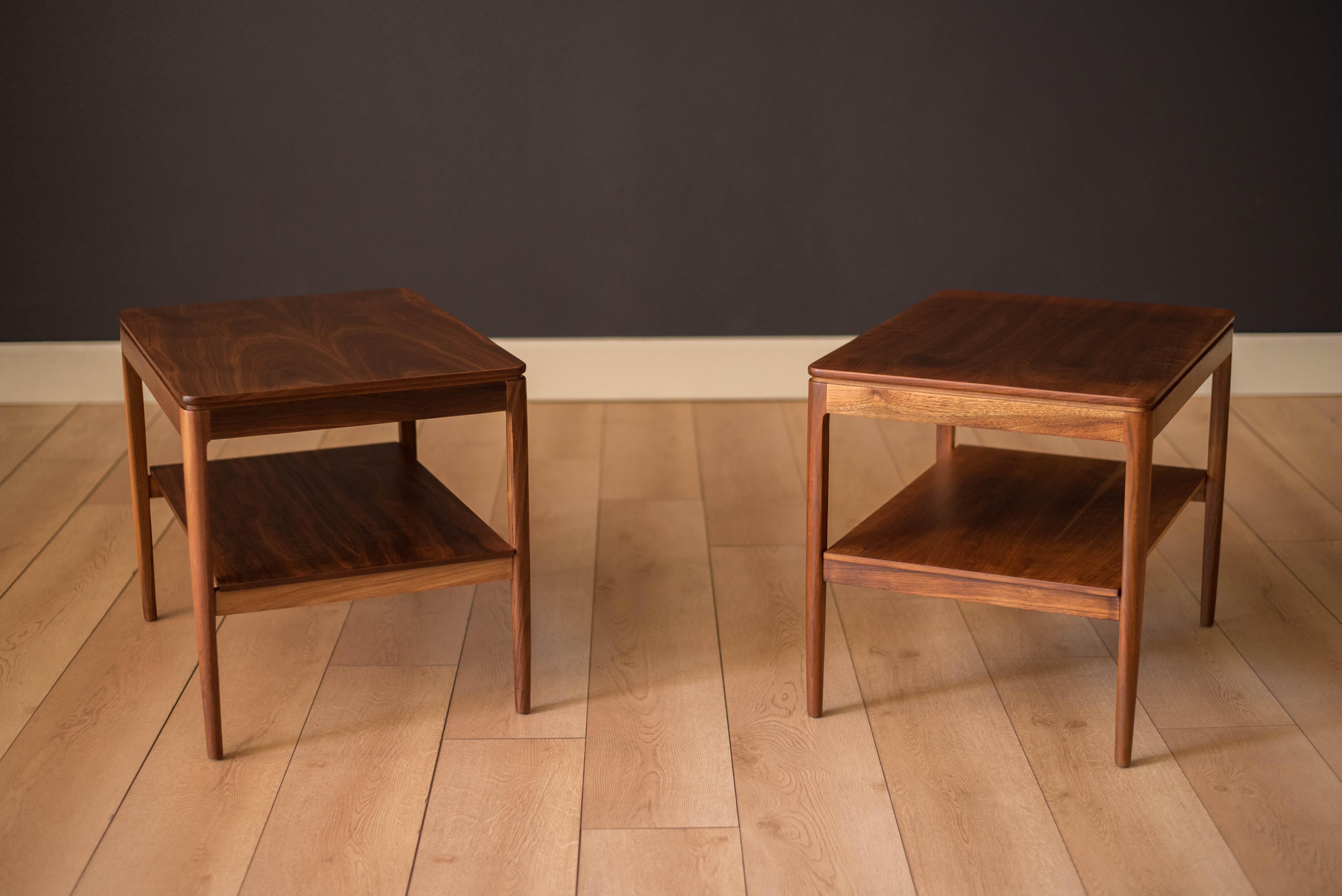 Vintage pair of side tables in walnut designed by Stewart McDougall & Kipp Stewart for Drexel Declaration. This set displays rich walnut grains and a two-tier shelf design. Price is for the pair.