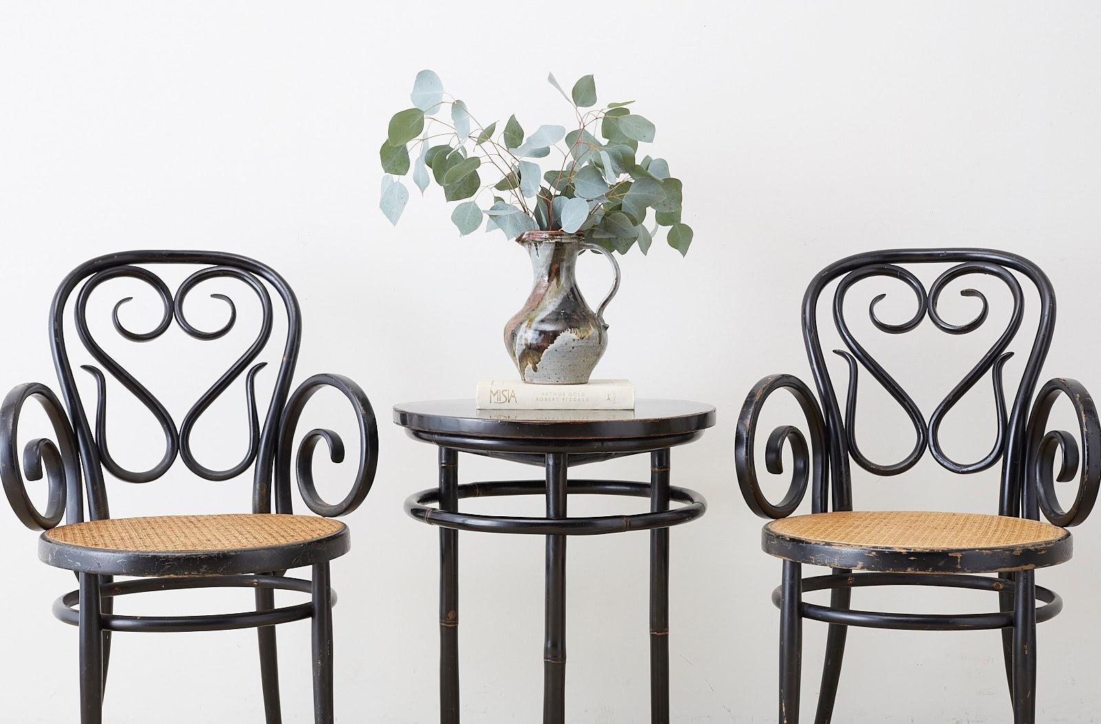 Stunning pair of Mid-Century Modern round bamboo drink tables featuring an ebonized lacquer finish. Elegant and Minimalist style with a round wood top supported by three round bamboo pole legs. The legs are conjoined by a bent bamboo ring stretcher.