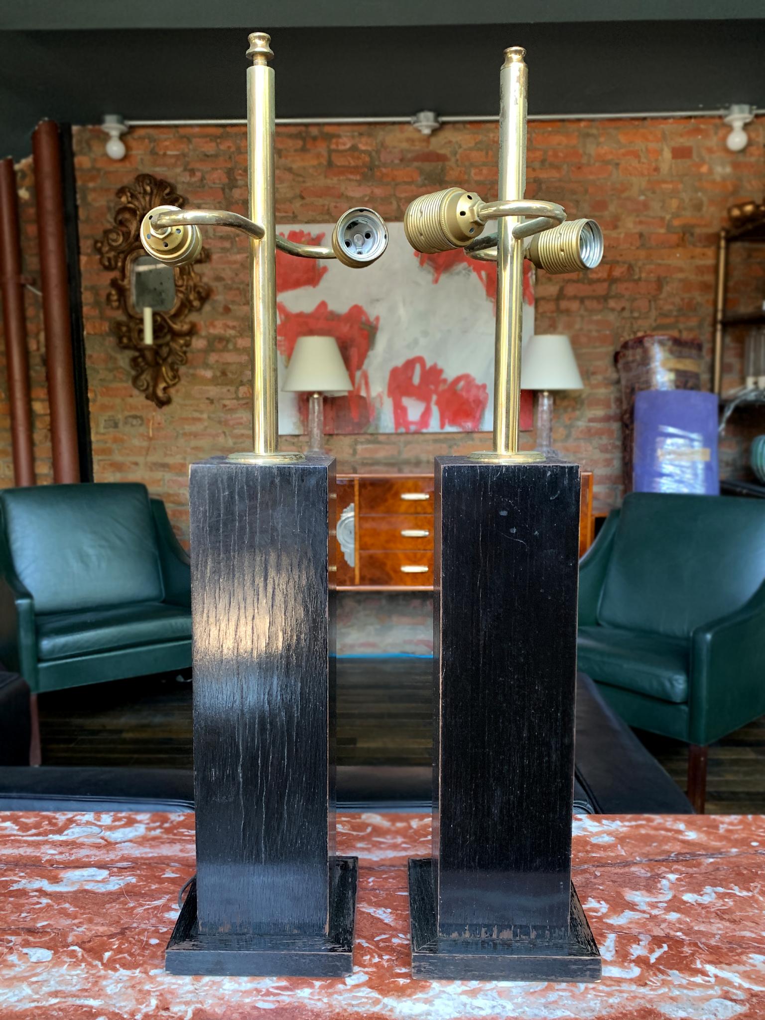 A pair of mid-20th century table lamps comprised of ebonized wood and brass hardware. Over the years the wood grain has shown through the finish, creating striations in the black lacquer. The result is a surface that's both glossy and textured. The