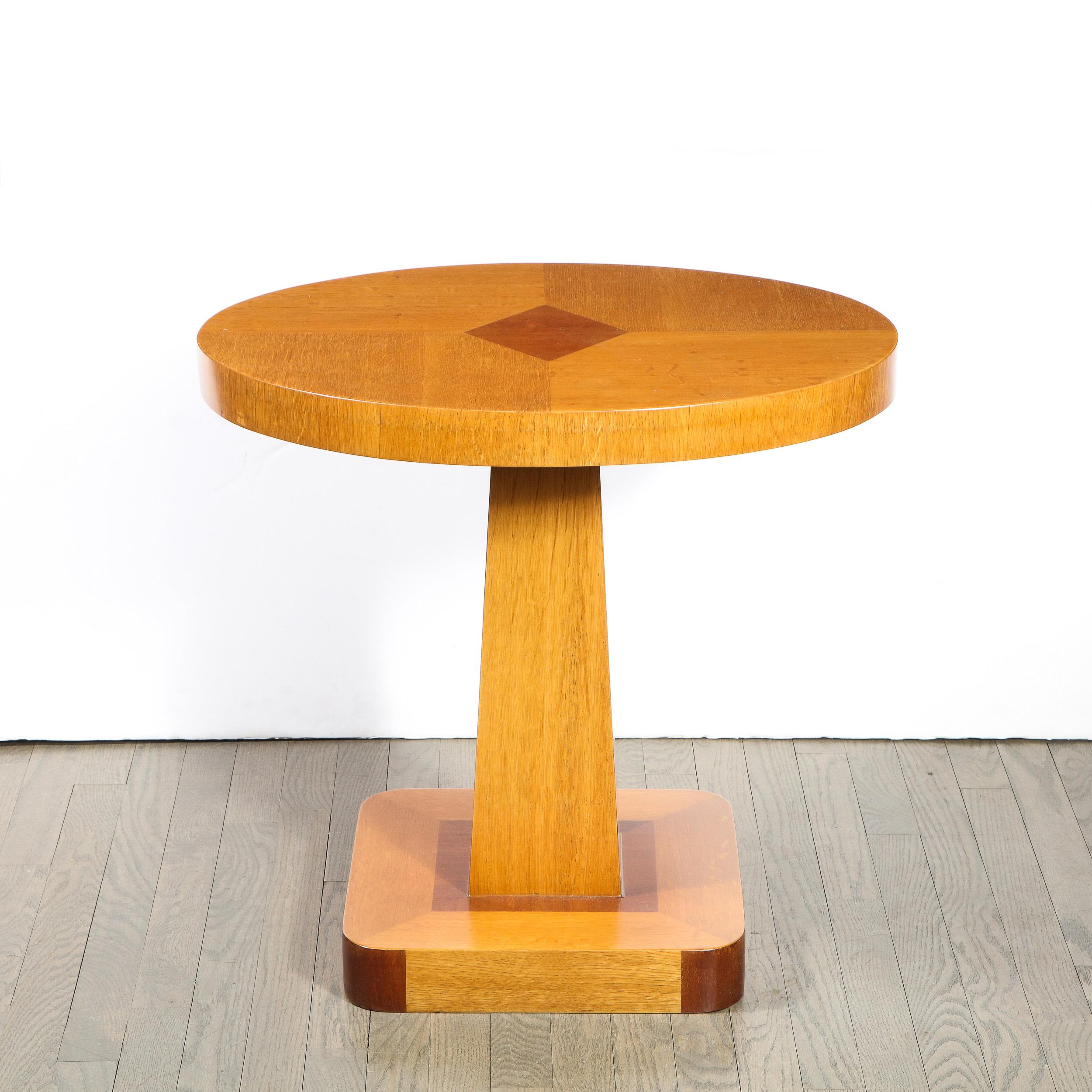 This stunning pair of Mid-Century Modern geometric oval occasional/ end tables were realized in the United States, circa 1950. They feature oval tops in hand rubbed bookmatched Elm with diamond form detailing inlaid in Walnut in the center of each.