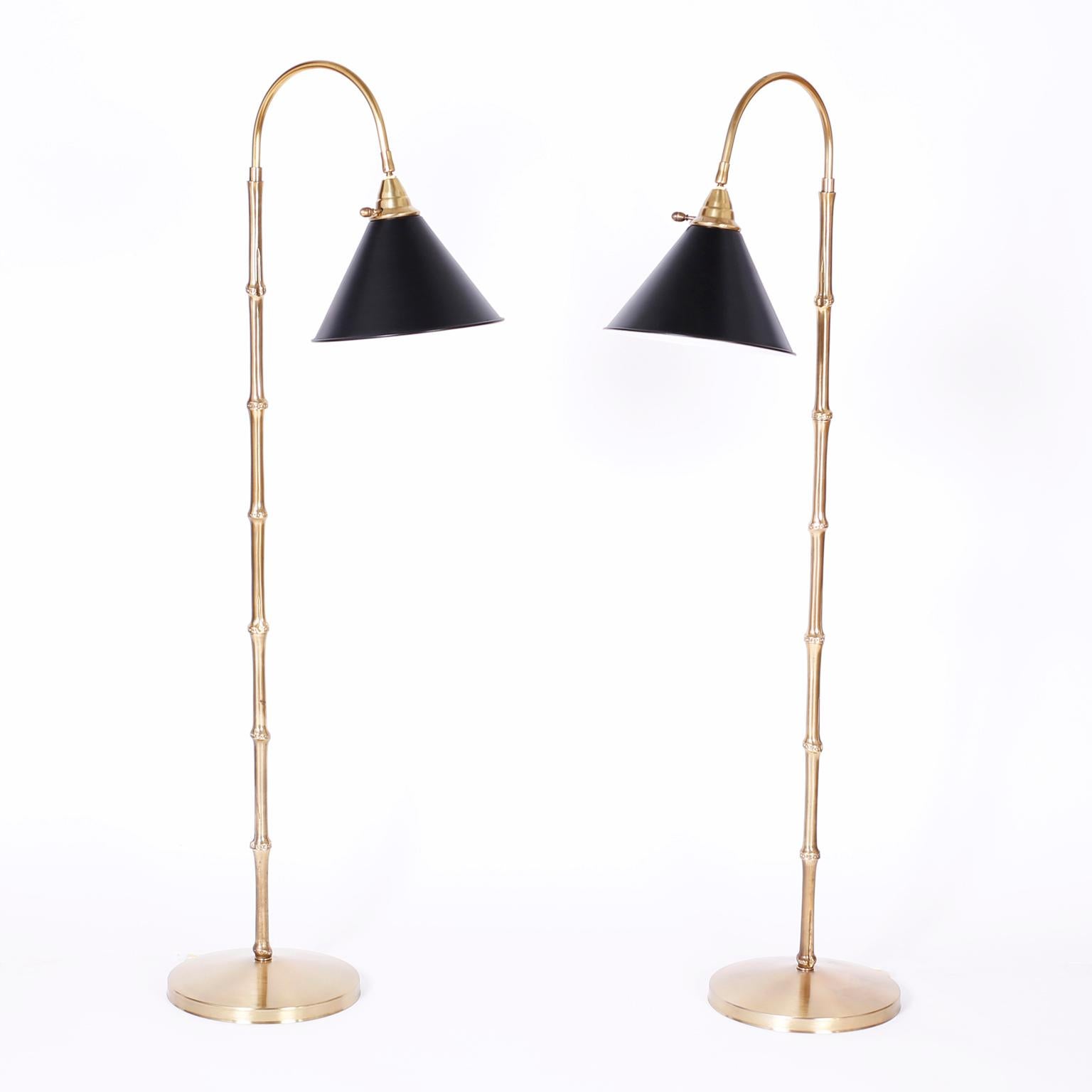 Chic midcentury pair of floor lamps with black shades that swivel on a brass gooseneck and stand with a faux bamboo motif on a round brass base. Hand polished and lacquered for easy care. Probably by Chapman.