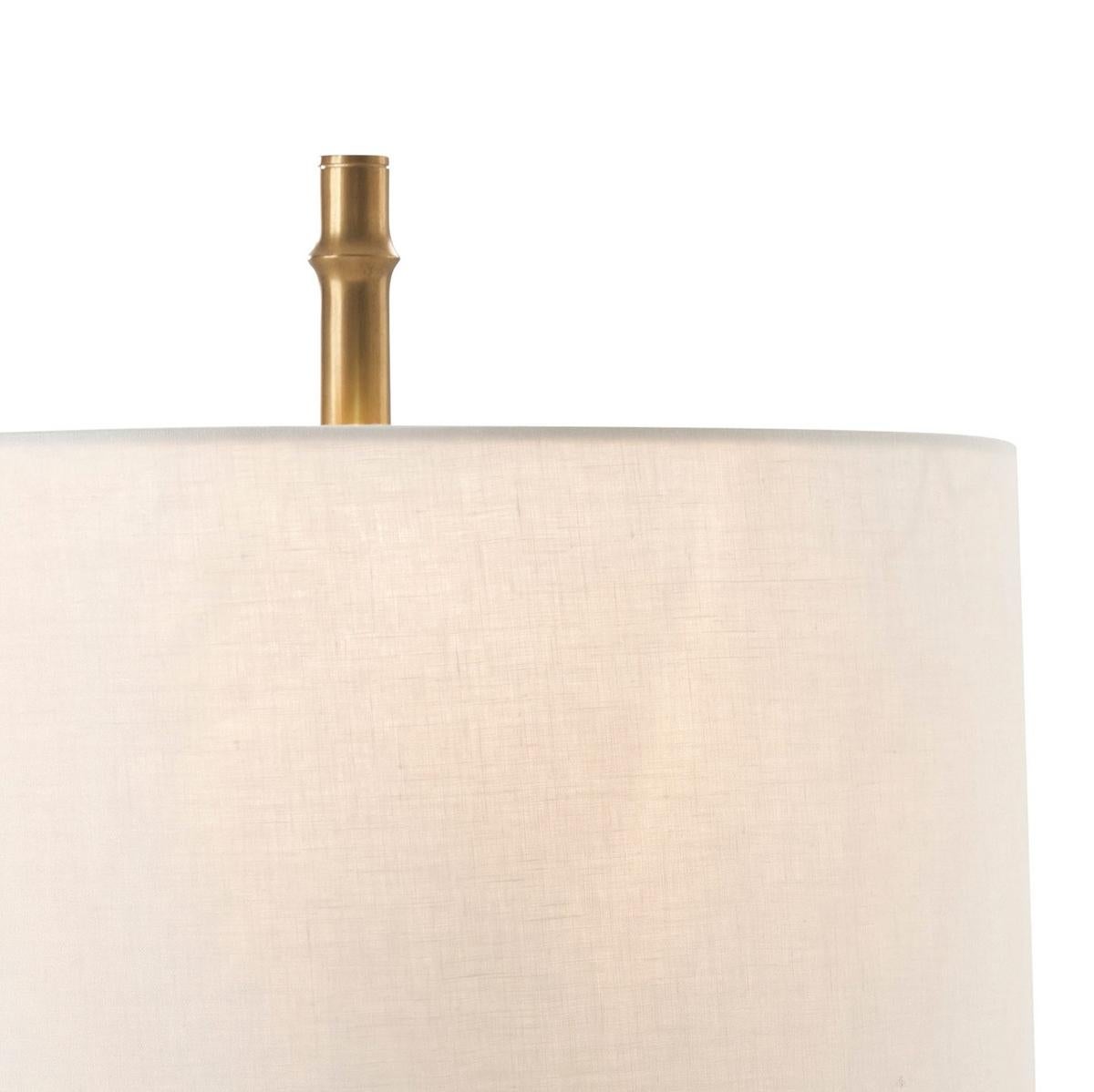 Featuring a unique satin brass-finished faux bamboo pedestal that beautifully complements its round linen shade, creating a warm and inviting glow in any room.

With a modern organic design, this lamp is not just a light fixture but a statement
