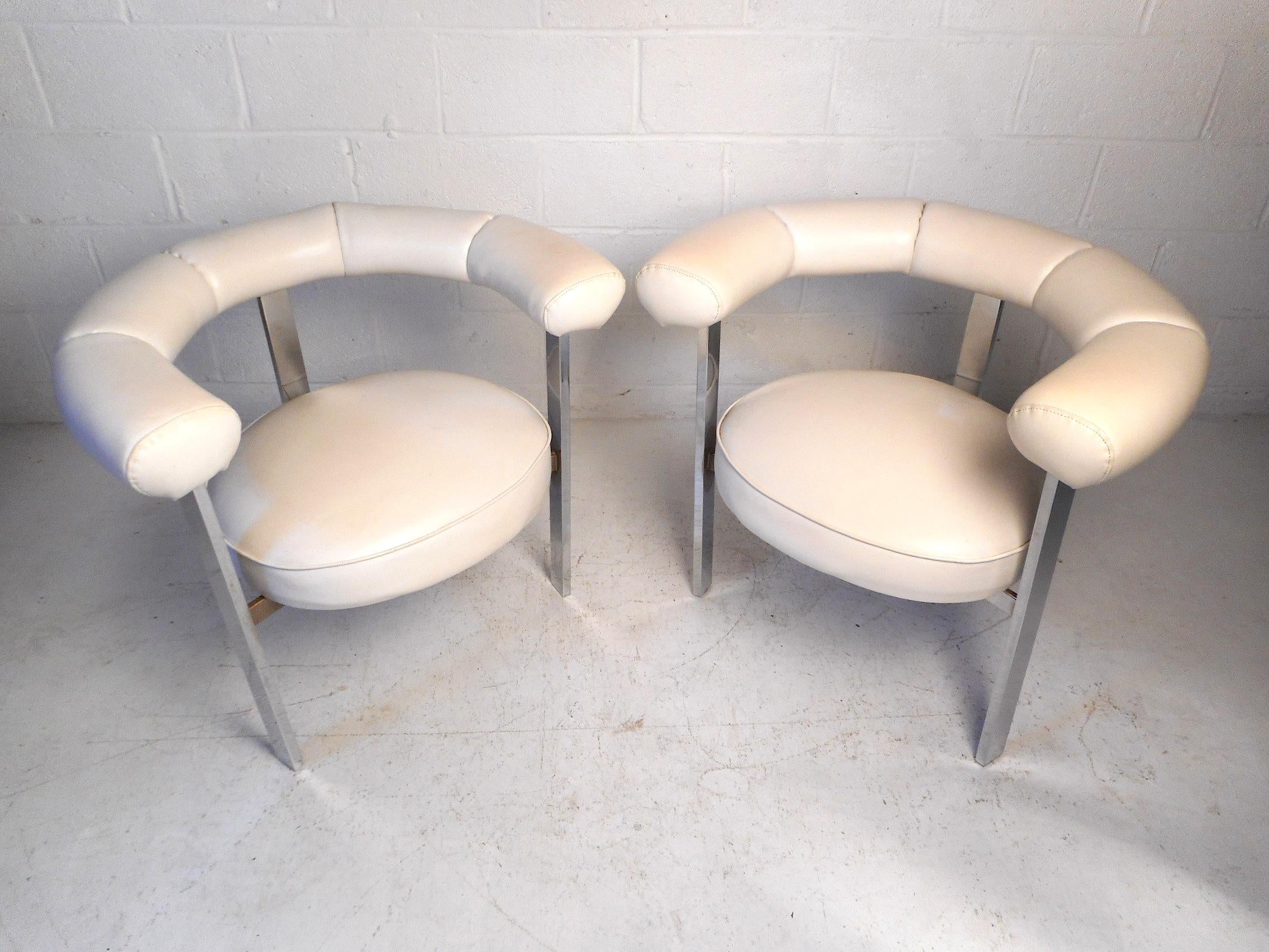 This impressive set of Mid-Century Modern barrel chairs feature a lovely white faux-leather upholstery supported by a sturdy chrome frame. These unique chairs are a perfect addition to any home, business, or office's modern interior. Please confirm