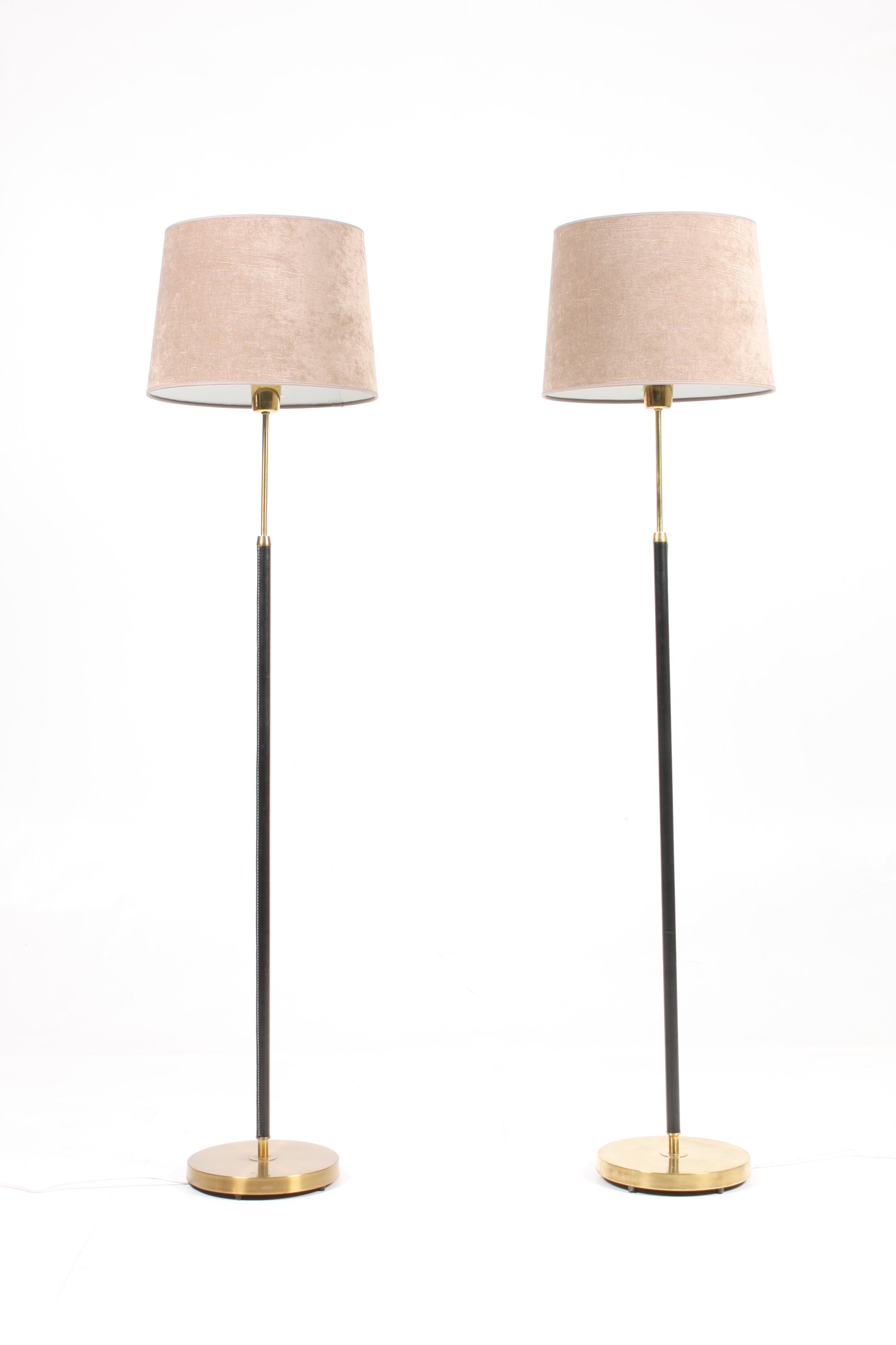 Pair of floor lamps covered in patinated leather on a round brass base. Designed and made in Sweden in the 1950s. Original condition.