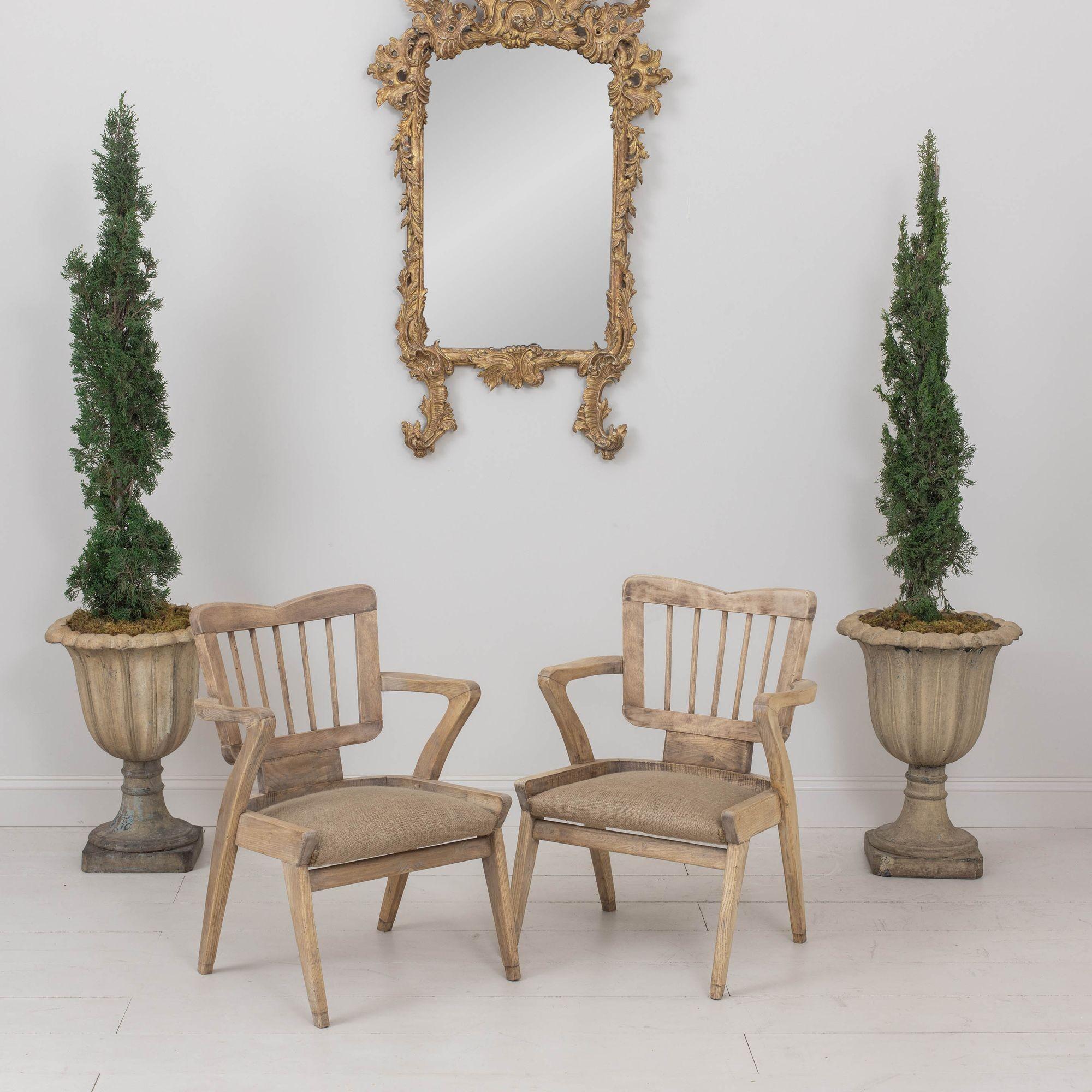 A unique pair of French armchairs in bleached beech wood from the mid 20th century. These stylish chairs have a natural, burlap seat with nail head trim.