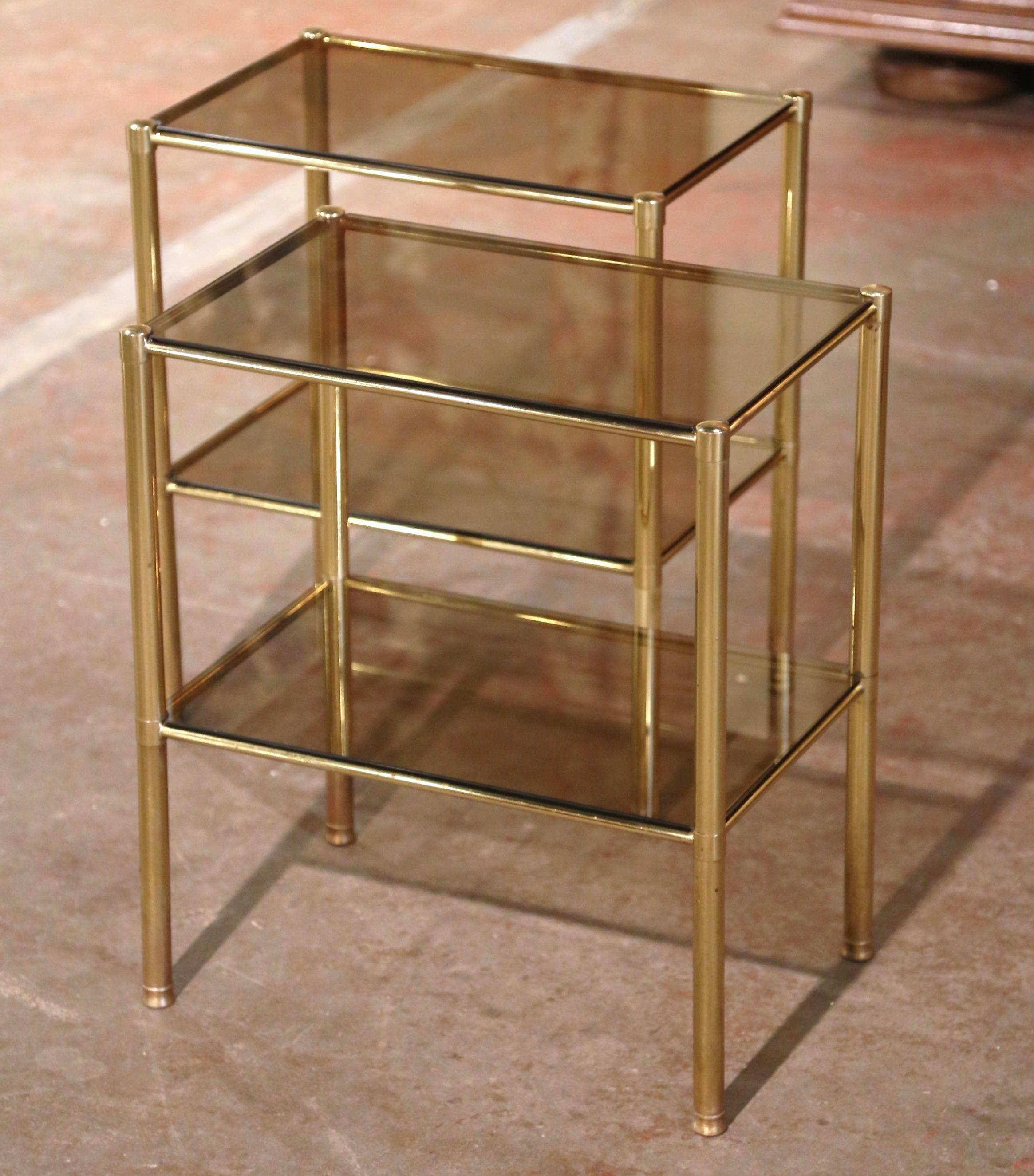 These elegant antique side tables were crafted in France circa 1960. Rectangular in shape and attributed to Maison Jansen in Paris, the delicate brass tables stand on four round legs embellished with bun feet at the base, and  dressed with