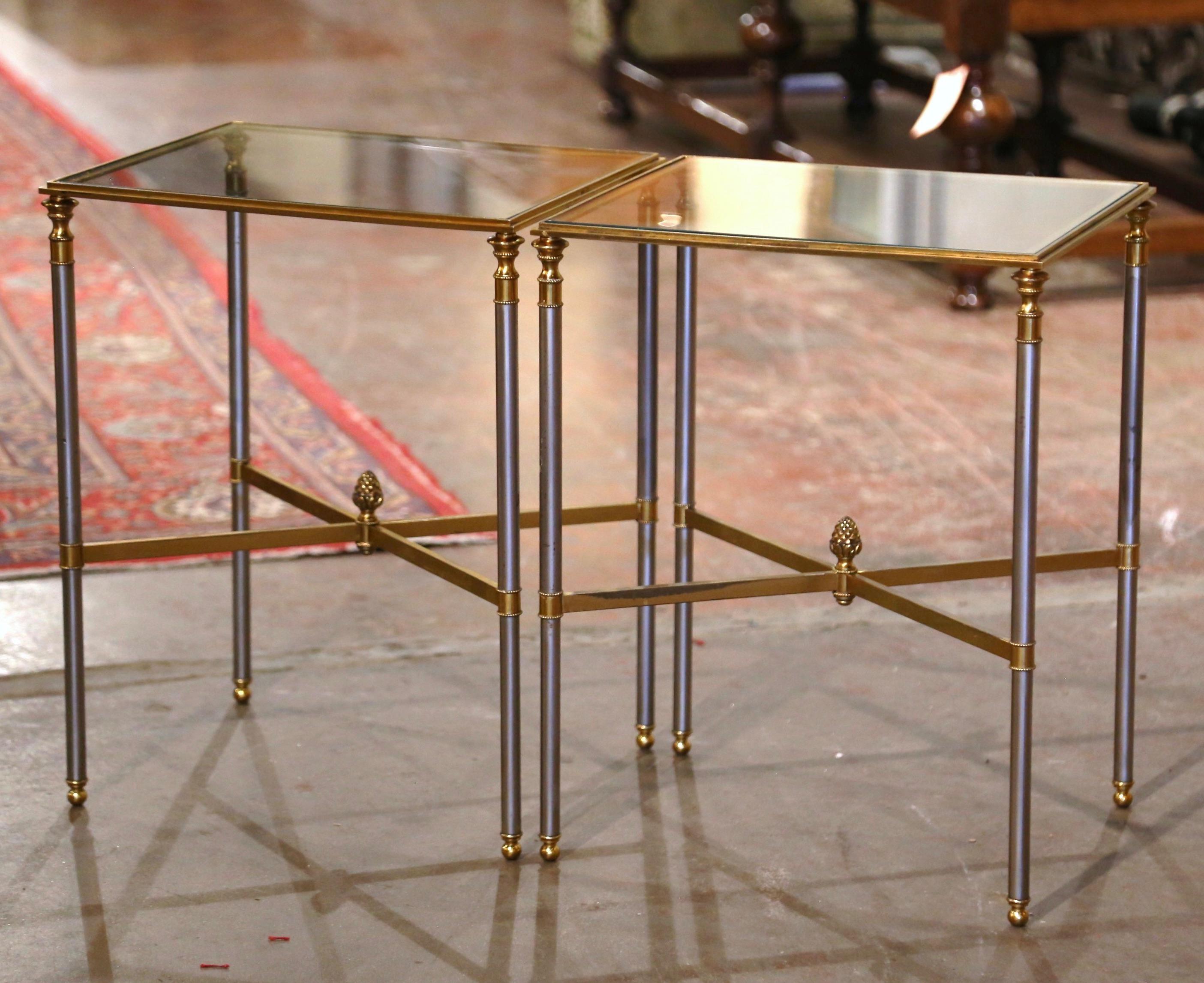 These elegant vintage side tables were created in Paris circa 1950 and attributed to Maison Jansen. Made of brass and steel, each table stands on long steel legs ending with brass ball feet and decorated with brass mounts at the shoulder; the table