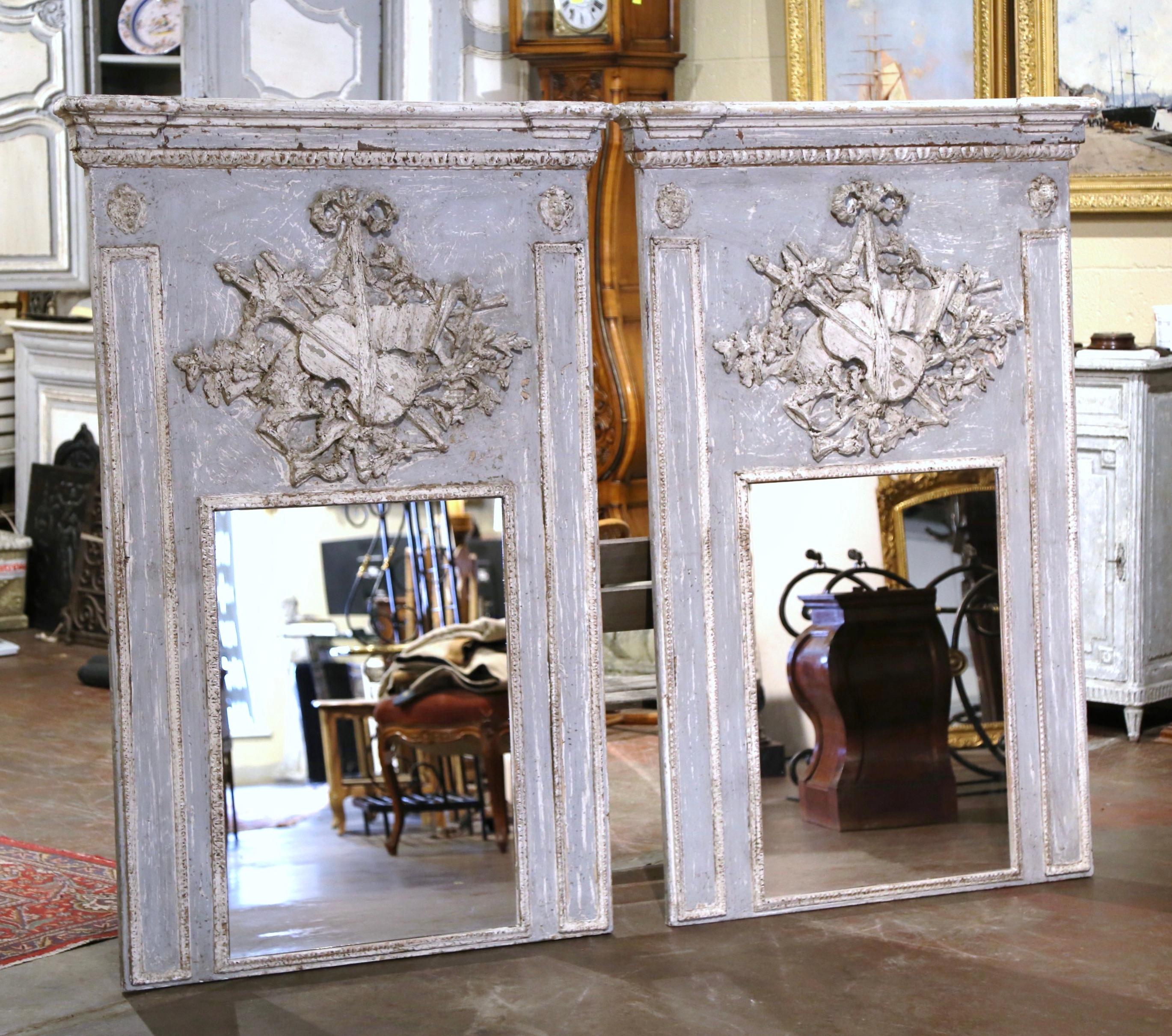 Decorate a living room, or even a master bathroom with this elegant pair of colorful antique trumeaux mirrors. Crafted in France, circa 1950, each trumeau is dressed at the pediment with a thick crown. Each wall piece features hand carved musical