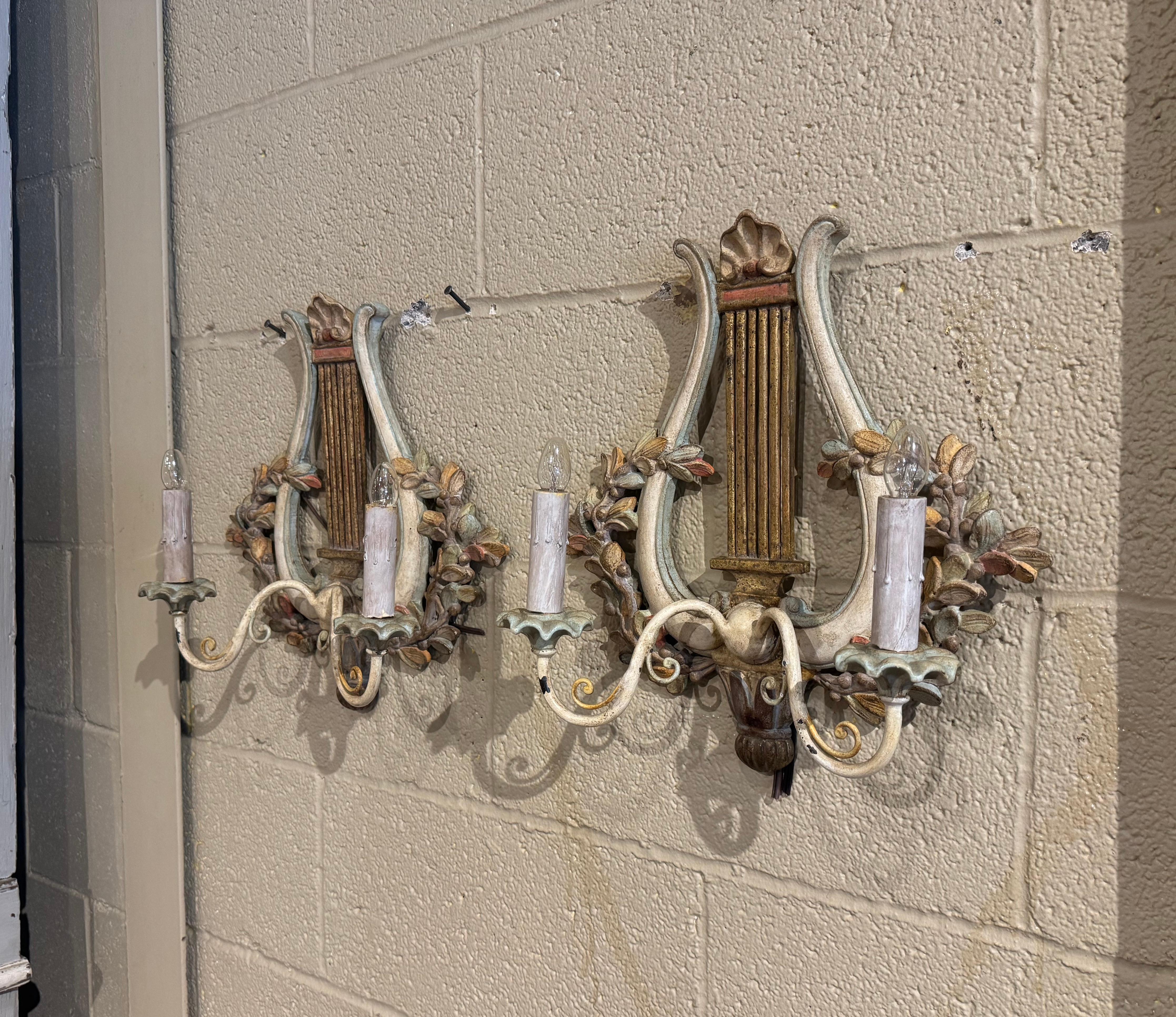 Améliorez l'ambiance d'un couloir ou d'une salle d'eau avec cette paire exquise d'appliques antiques colorées. Fabriquée en France vers 1970, chaque applique à deux lumières s'inspire de la lyre classique, un symbole étroitement lié à la musique et