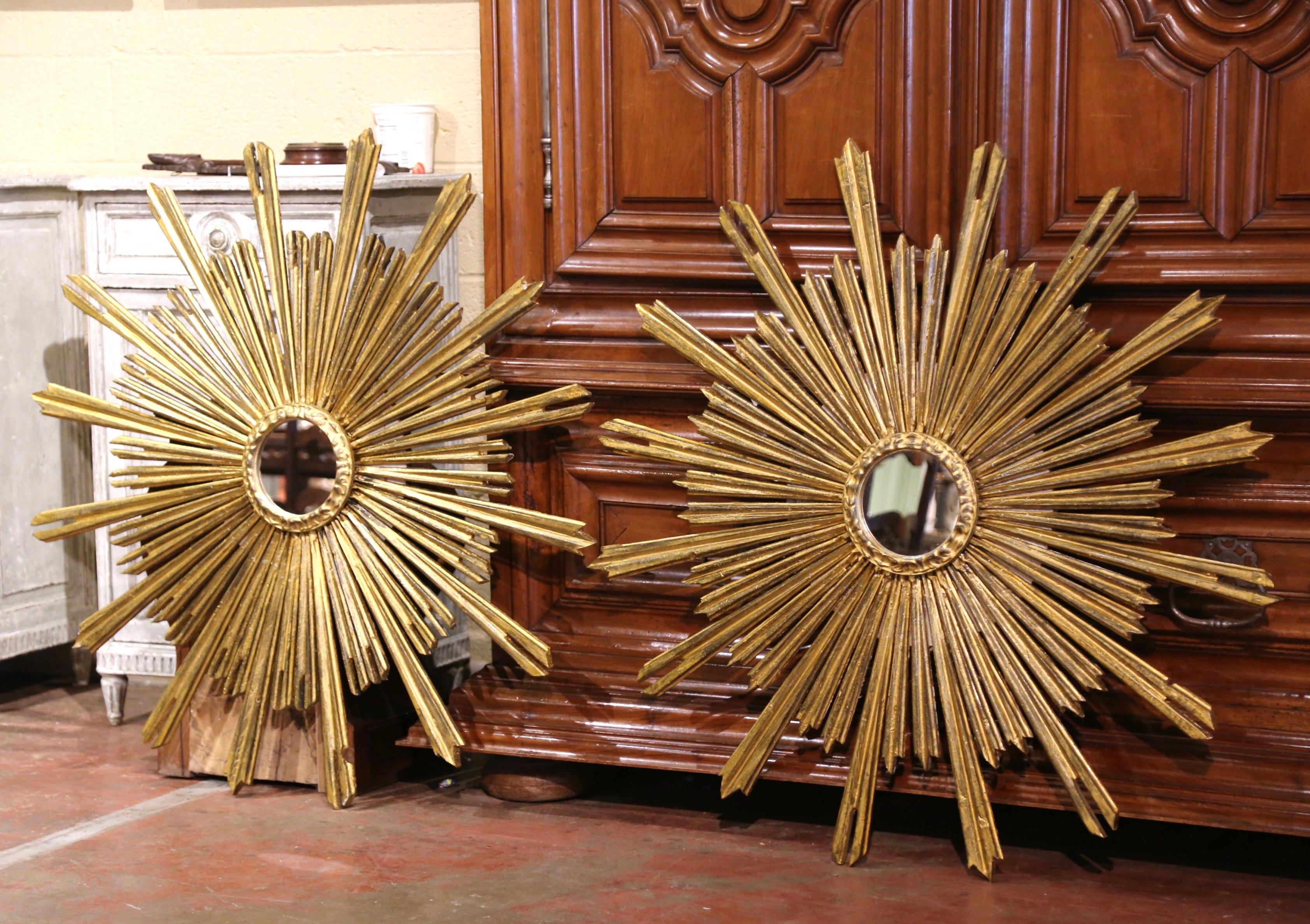 Add a beautiful shine to your home with this large pair of eye-catching sun mirrors. Created in France circa 1960, each carved mirror has a Classic Sunbeam shape, a round convex glass in the center, and a rich rubbed gold leaf painted finish. Both