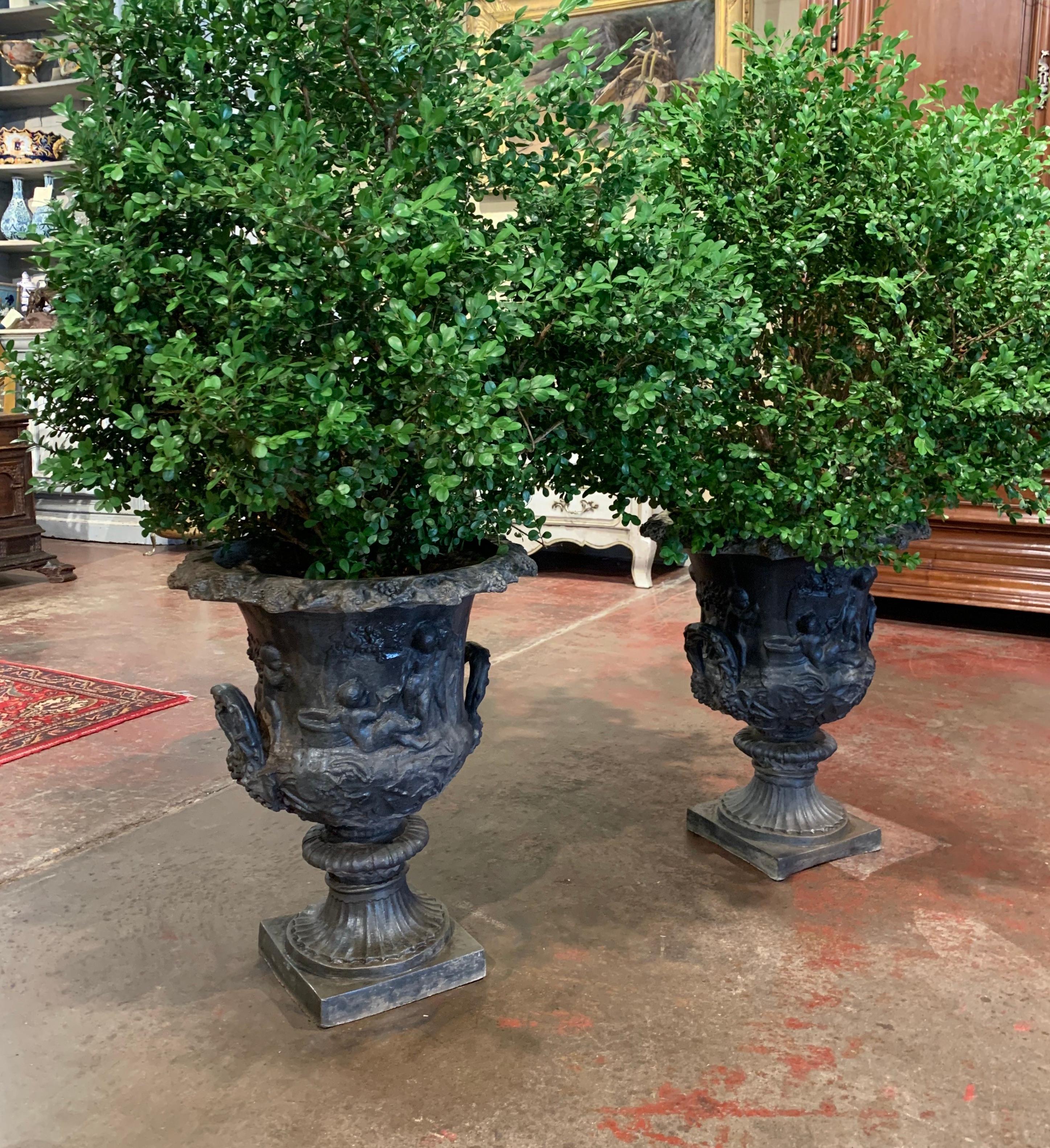 Decorate a front or backyard with this elegant pair of neoclassical outdoor jardinière, crafted in France circa 1950 and made of heavy lead, each pot with square base features a scalloped rim over two side handles and is decorated with allegoric