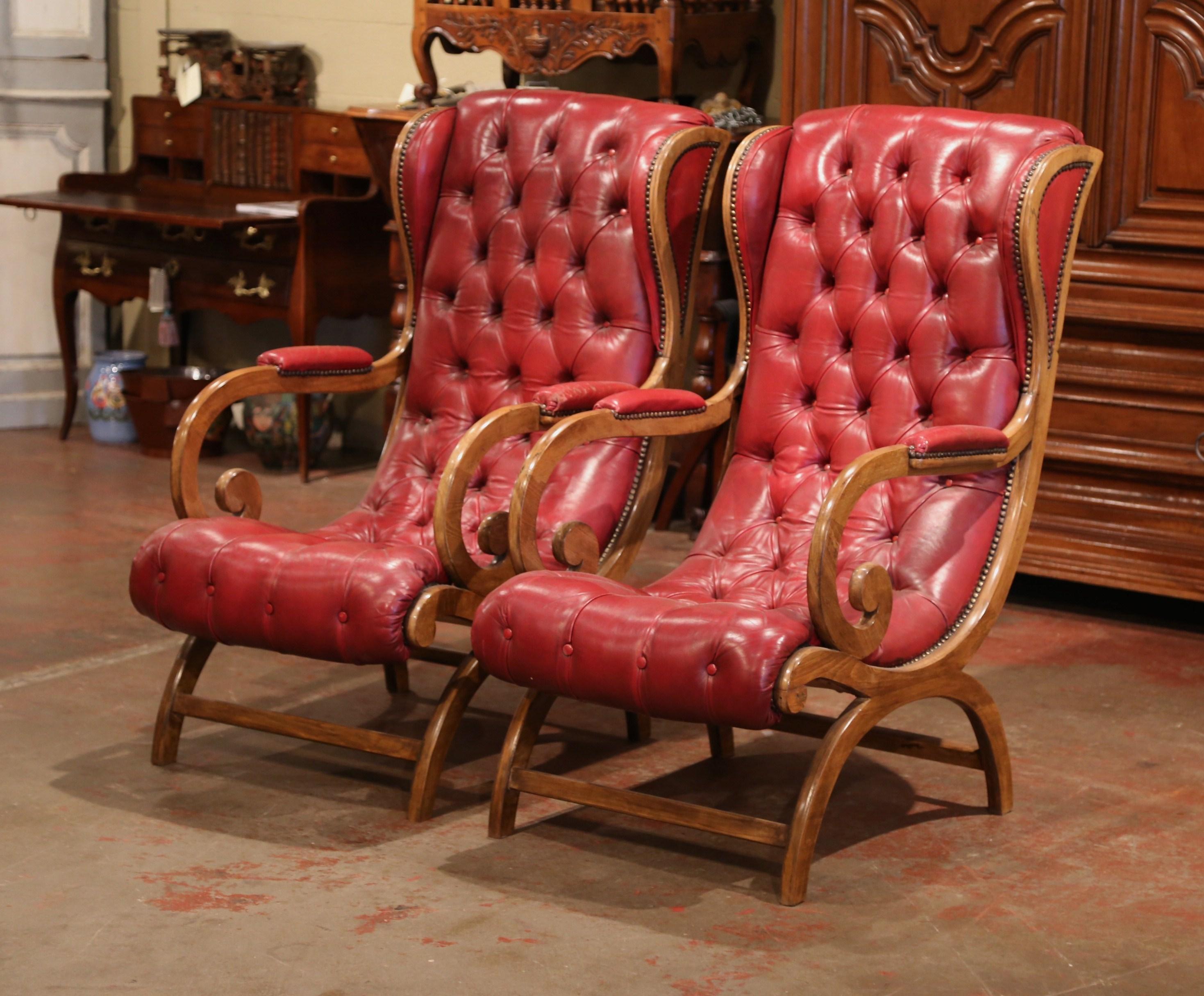 This elegant pair of vintage armchairs was crafted in France, circa 1950. The oversized fruitwood club chairs have a tall, comfortable back with ears and dramatic, curving, upholstered armrests. The chairs both have curved legs in the rounded half