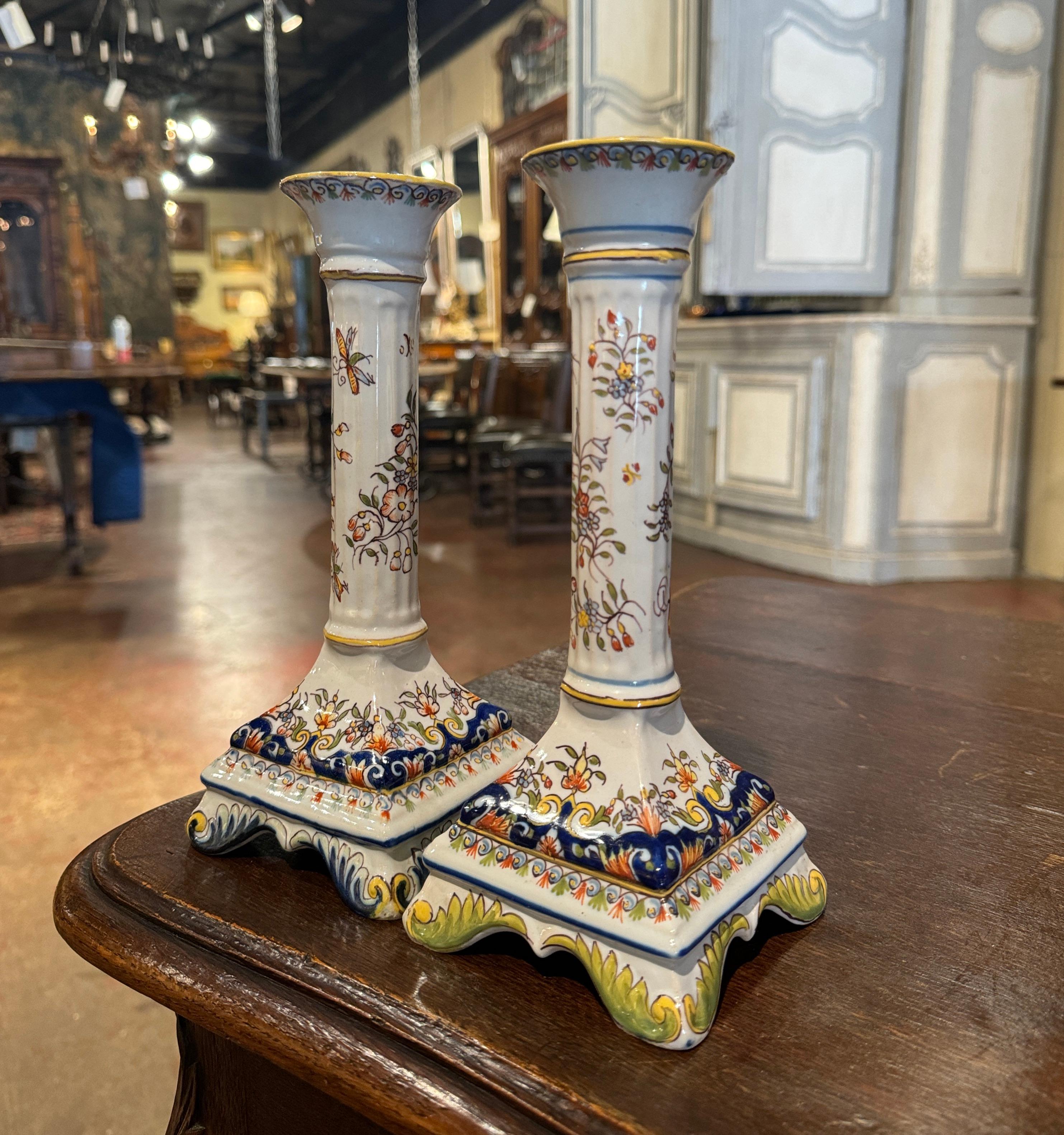 Realizzato a Rouen, in Normandia, Francia, intorno al 1960, ogni colorato candeliere poggia su piedi a voluta decorati con motivi di foglie d'acanto e su un grembiule smerlato. Ogni portacandela in maiolica è decorato con motivi floreali e di foglie