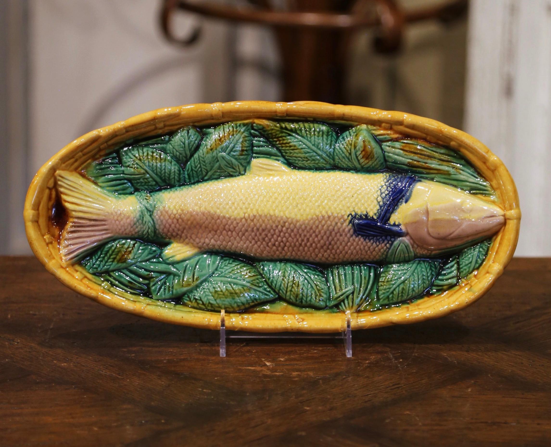 Decorate a wall or a shelf with this colorful pair of vintage Majolica fish platters. Crafted in France, circa 1960, and oval in shape, each ceramic subject features a Daurade (European bass) fish sculpture in high relief in a weave basket, and