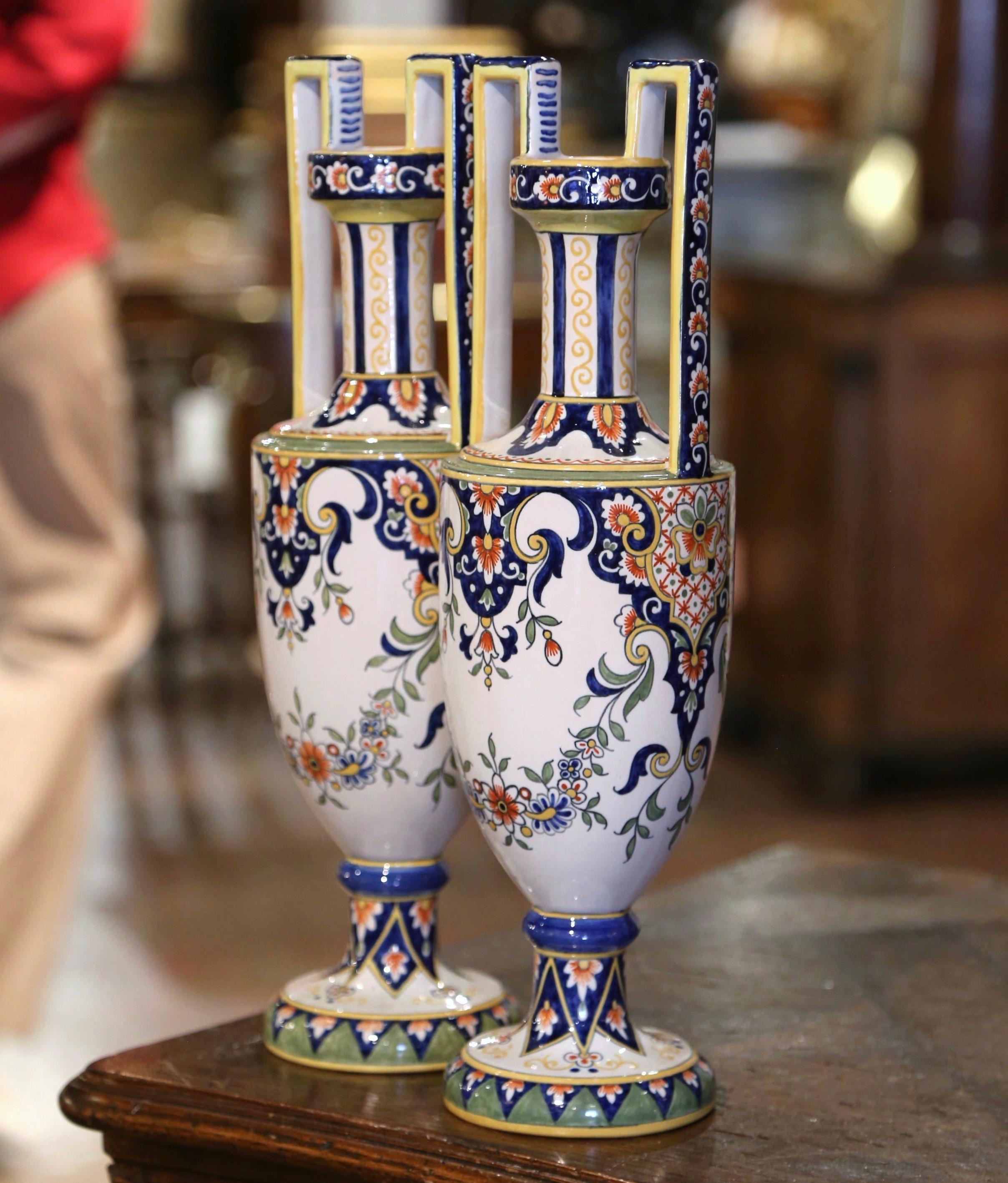 Décorez une cheminée ou une table avec cette paire de vases colorés en faïence ancienne. Fabriqué en Bretagne, France, vers 1960, chaque vase repose sur une base ronde et est habillé de larges poignées latérales au-dessus d'un haut col. Les deux