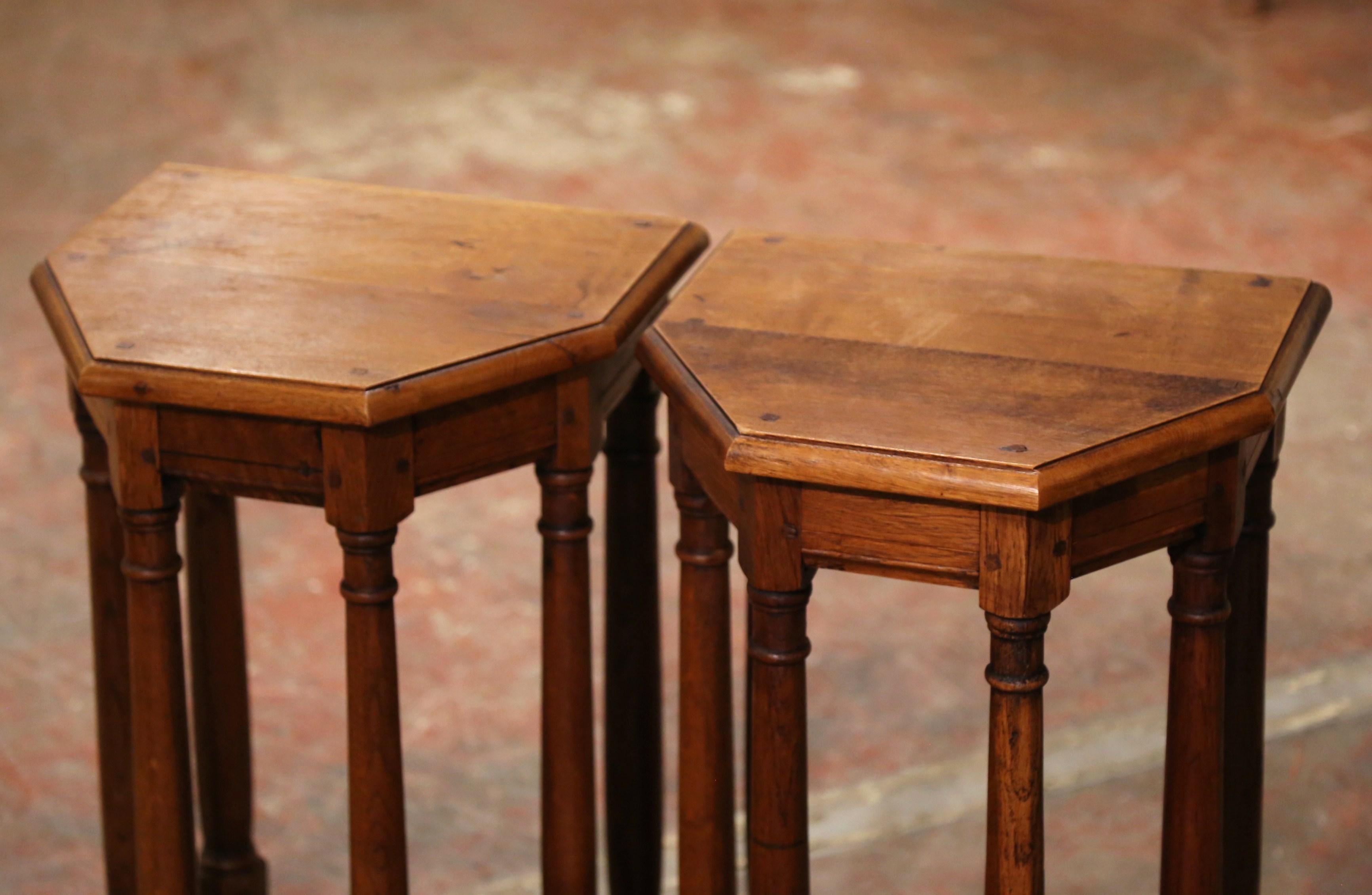 This elegant antique side tables were created in France circa 1960. Built of oak, the piece stands on six turned legs connected with a sturdy stretcher at the bottom. The top surface is angled across the front. The versatile demi-lune country