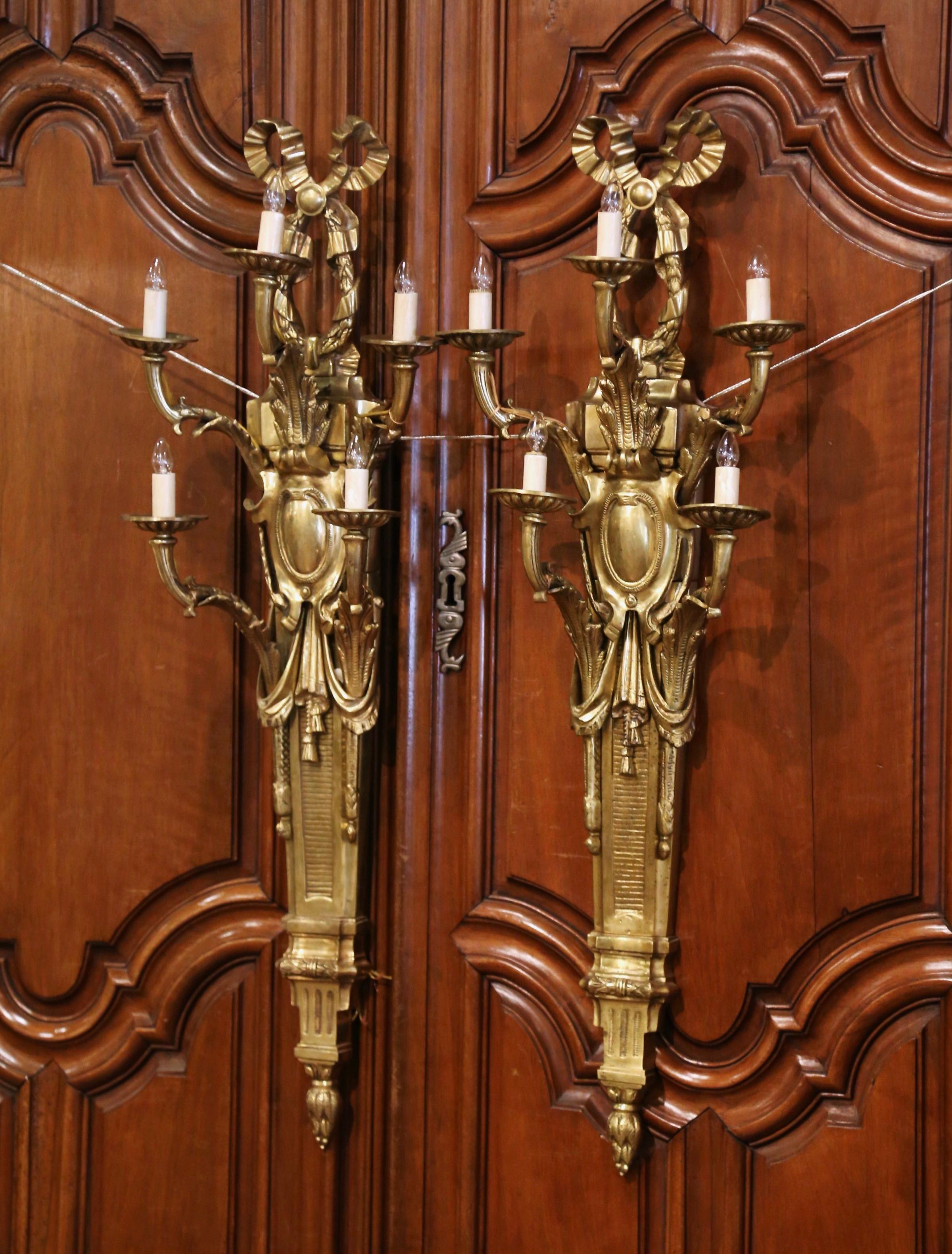 These large and elegant antique bronze sconces were crafted in France, circa 1960. Each wall sconce has five lights newly wired, and features a traditional Louis XVI ribbon bow at the pediment, with acanthus leaves, garland and swag motifs