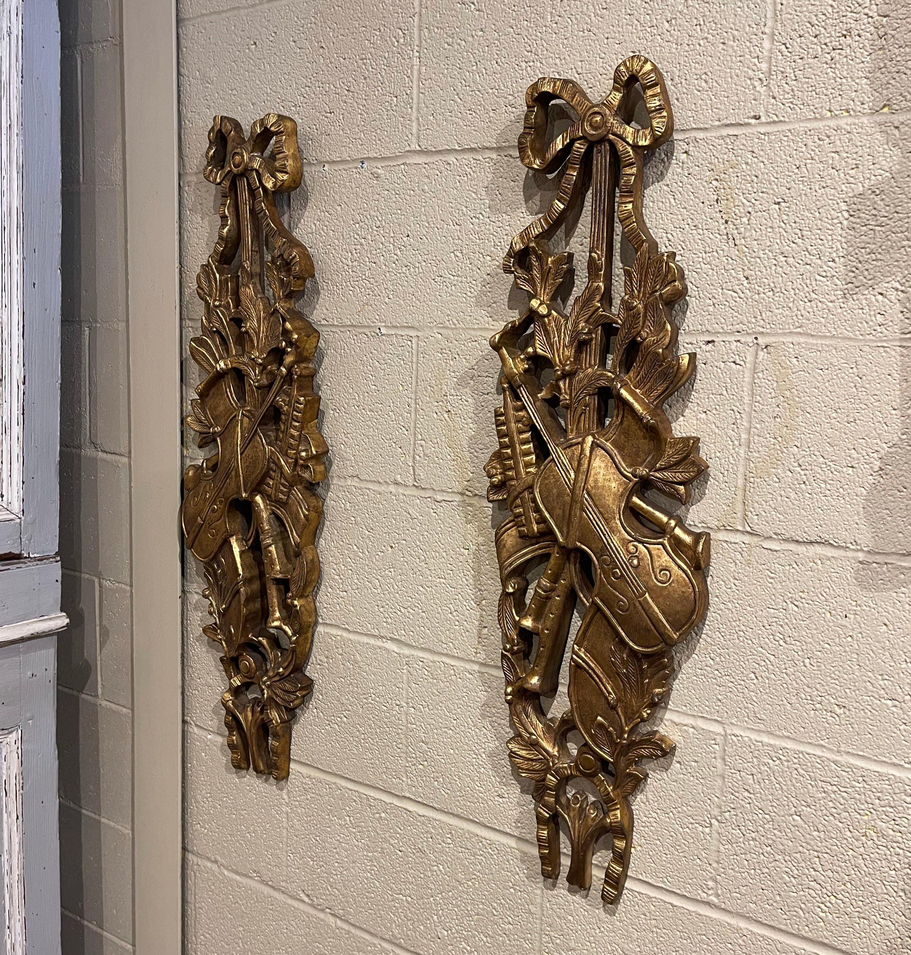 Decorate a dining room or living room with this elegant pair of antique wall carvings. Hand carved in Italy circa 1970 and almost 3 feet tall, each trophy features the traditional Louis XVI ribbon bow at the pediment, and carved twisted rope
