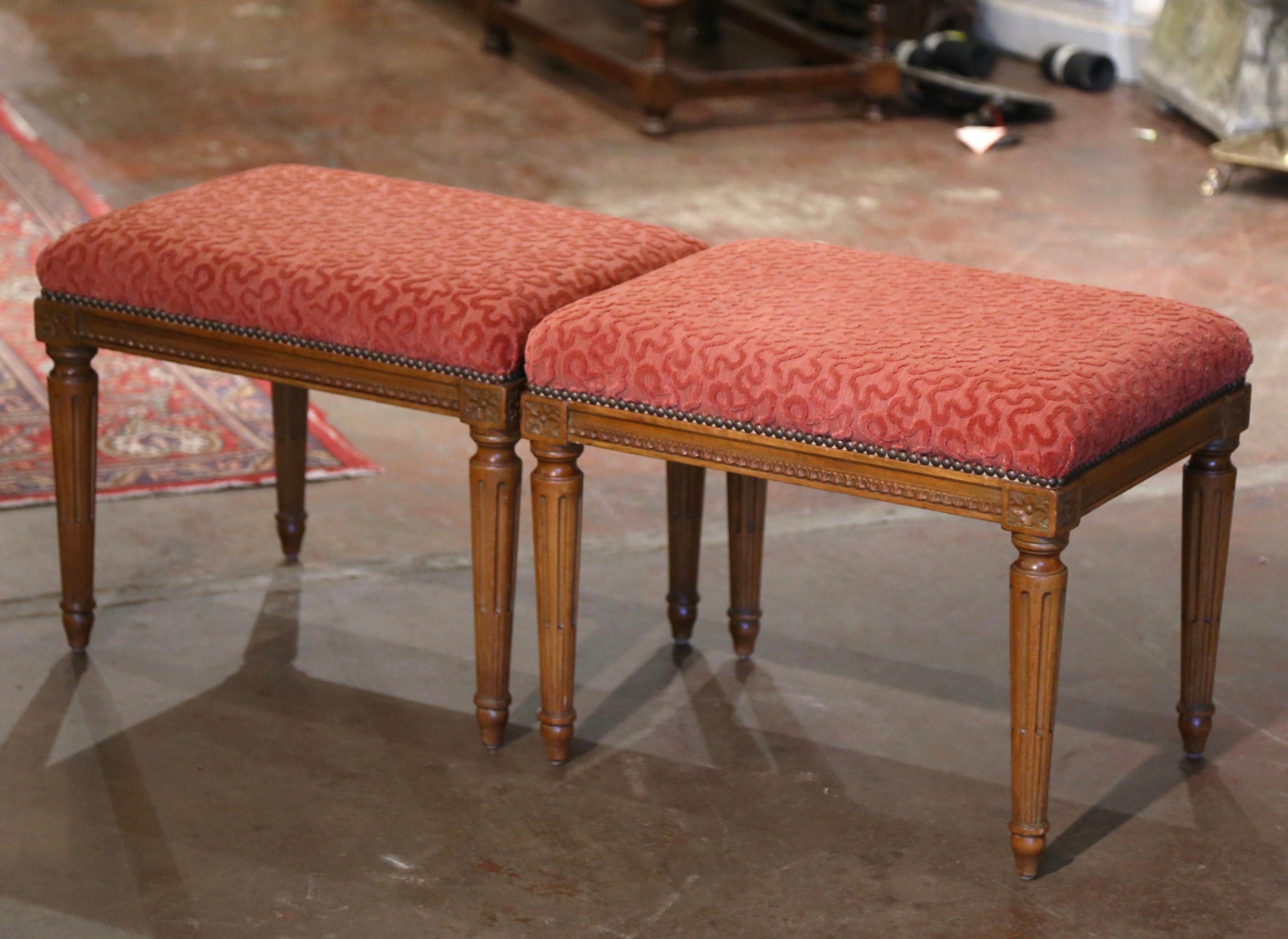 Bring extra seating to your den or living room with this elegant pair of vintage stools benches. Crafted in France, circa 1960 and rectangular in shape, each antique bench stands on tapered and fluted legs decorated with hand carved floral rosettes