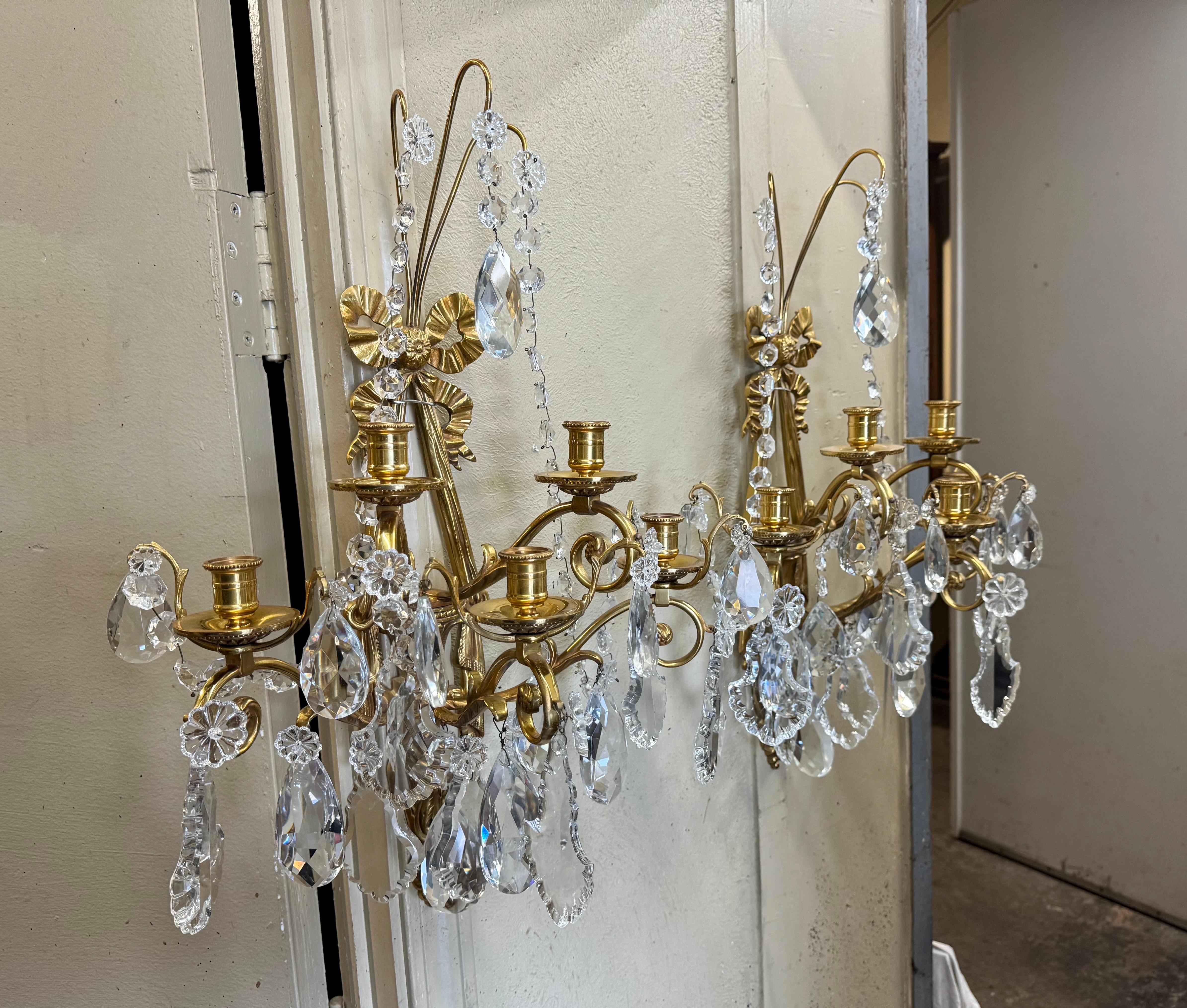 Decorate a powder room or living room with this elegant pair of antique gilt sconces. Crafted in France, circa 1960, each fixture features the traditional Louis XVI ribbon bow at the pediment, swag motifs on the sides and ending with grape decor and