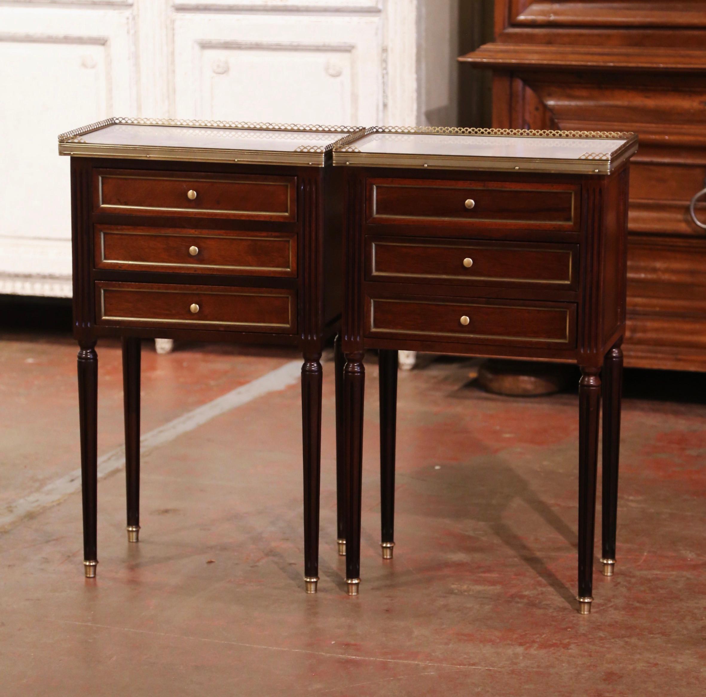 For sophisticated nightstands, look no further than these elegant antique bedside tables. Crafted in France circa 1940, the mahogany nightstands sit on four tapered legs ending with brass capped feet, and features three drawers decorated with brass