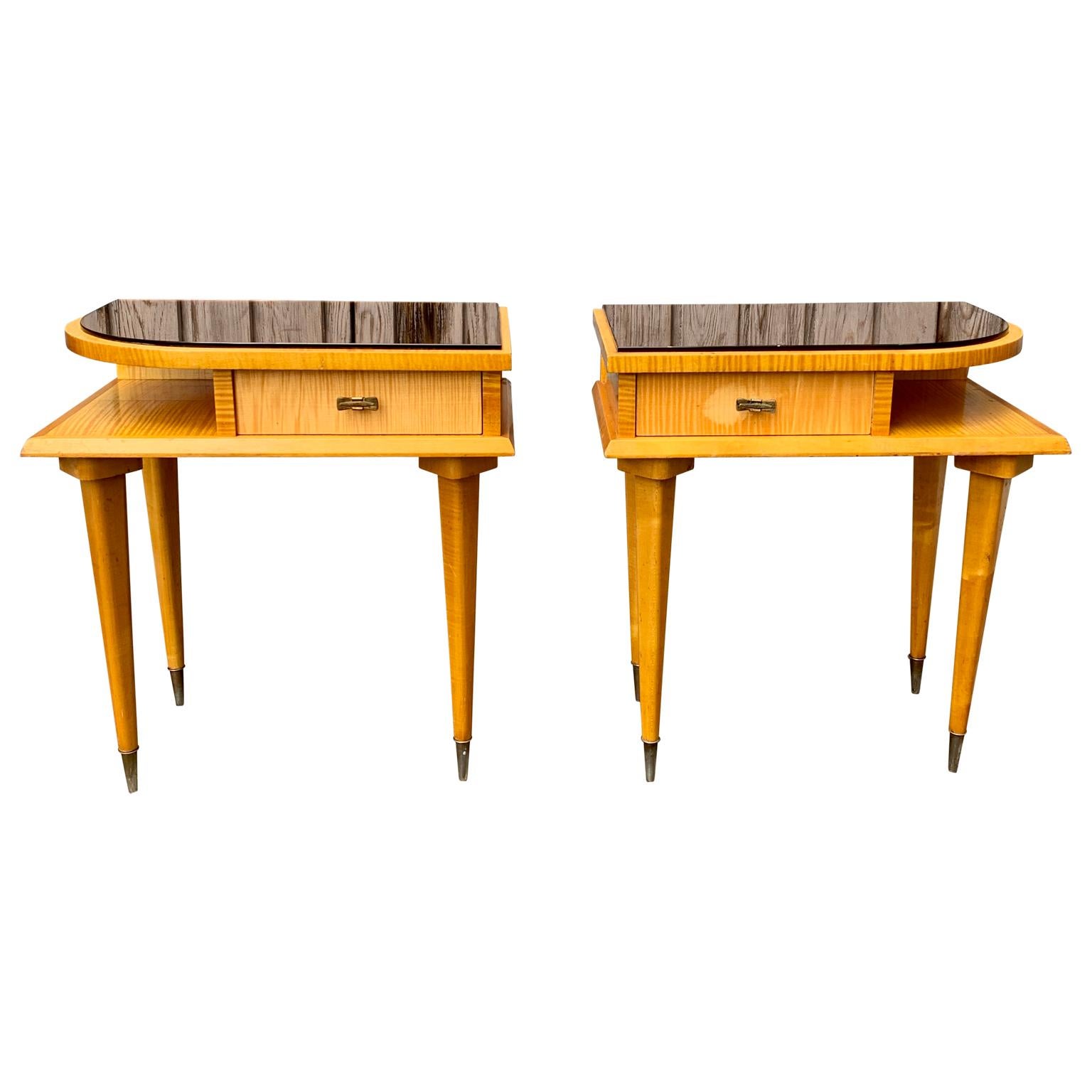 A pair of French design nightstands or small night tables in birch wood with the original brass handles and light warm pink glass on top. This unusual pair of vintage nightstands were produced by Ameublement N.F. 