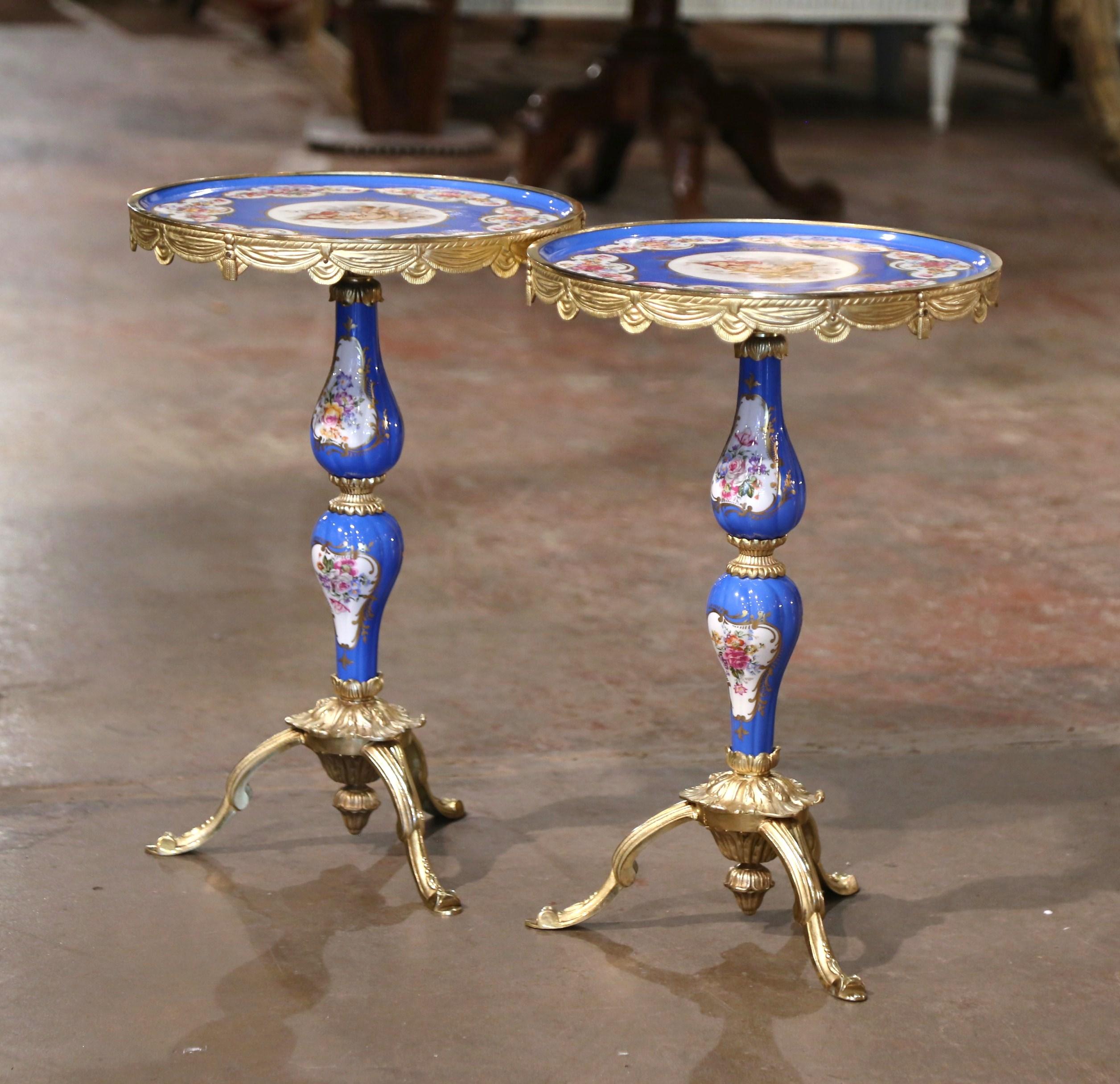 Decorate a living room or a den with this colorful pair of bronze dore and porcelain side tables. Crafted in Paris, France and attributed to the Sevres Manufacture, each small table stands on a bronze tripod base with curved legs ending with scroll