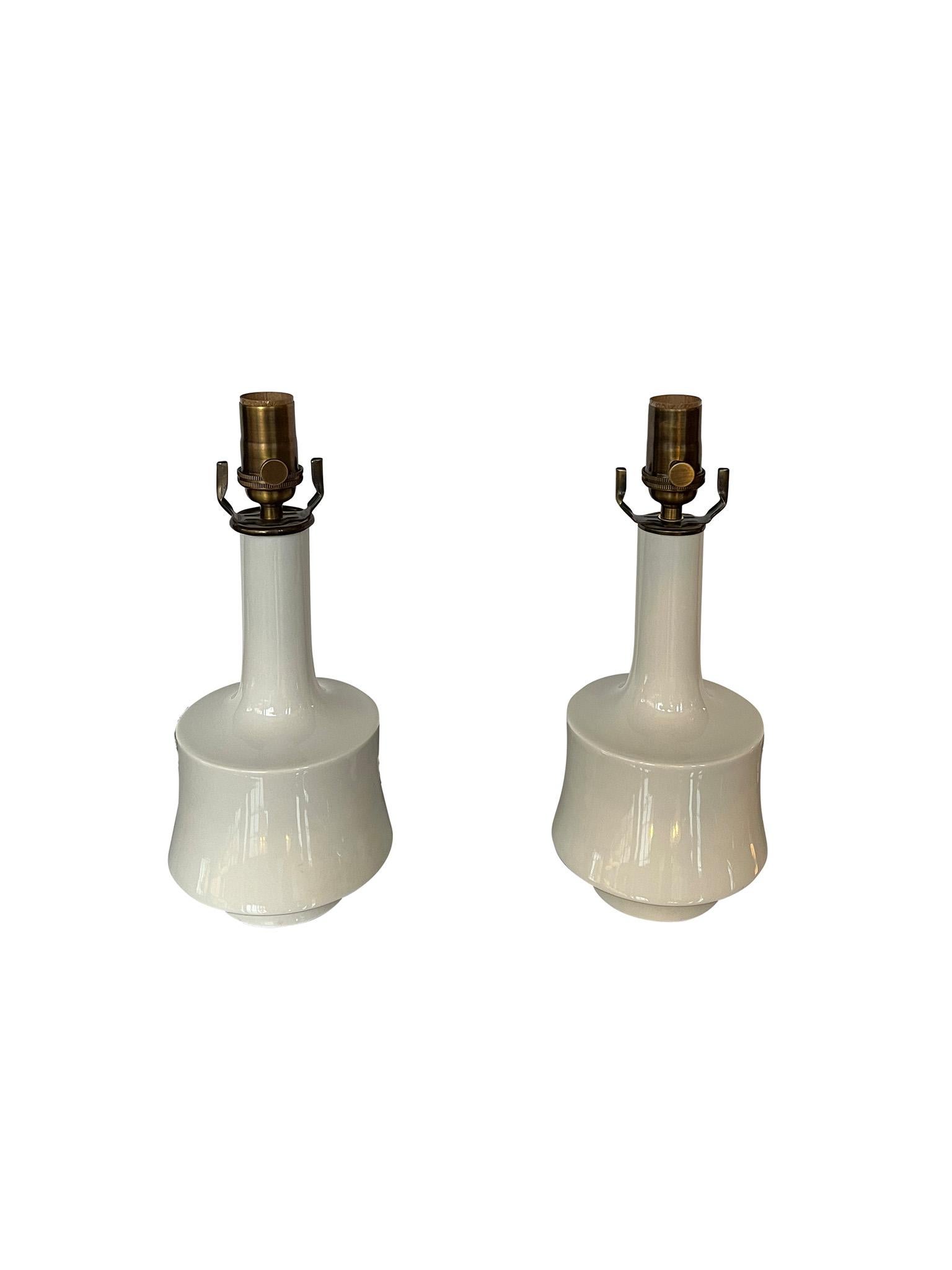 Charming pair of small 1960s midcentury white porcelain table lamps, manufactured in Bavaria, Germany. A perfect addition to any bedside table, these lamps are newly rewired and fitted with complementing white cotton-linen bell lampshades. Marked