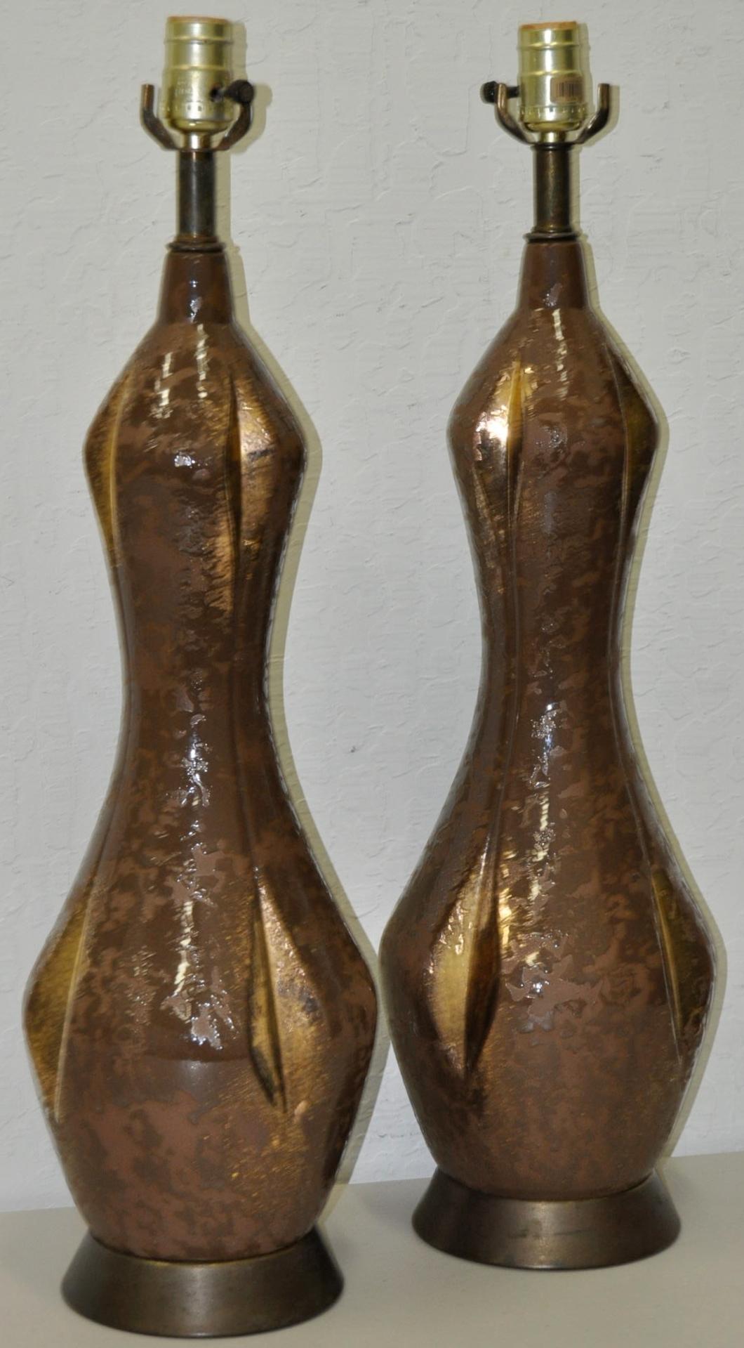 Impressive pair of midcentury gilded glaze ceramic table lamps circa 1950. 

Rich earth tones with subtle gilded underglaze. 

These tall, graceful lamps are in excellent condition and will light up any room. 

Wired and ready to illuminate.