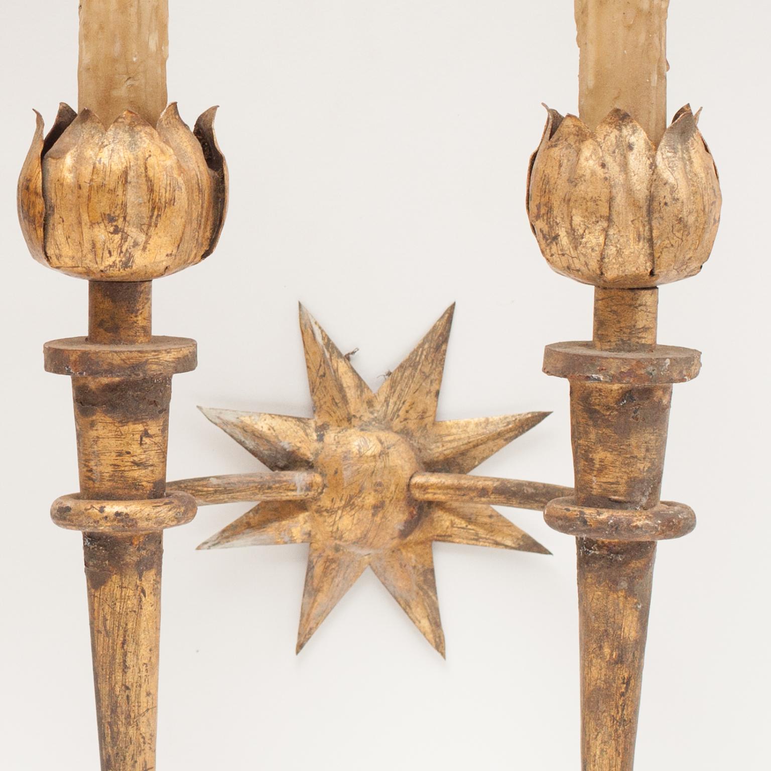 Pair of gold patinated wrought iron wall sconces Gilbert Poillerat style. The wrought iron becomes decoration of flames in the lower part, and in flower petals in the upper part, they rest on a golden star. Each sconce is newly rewired.