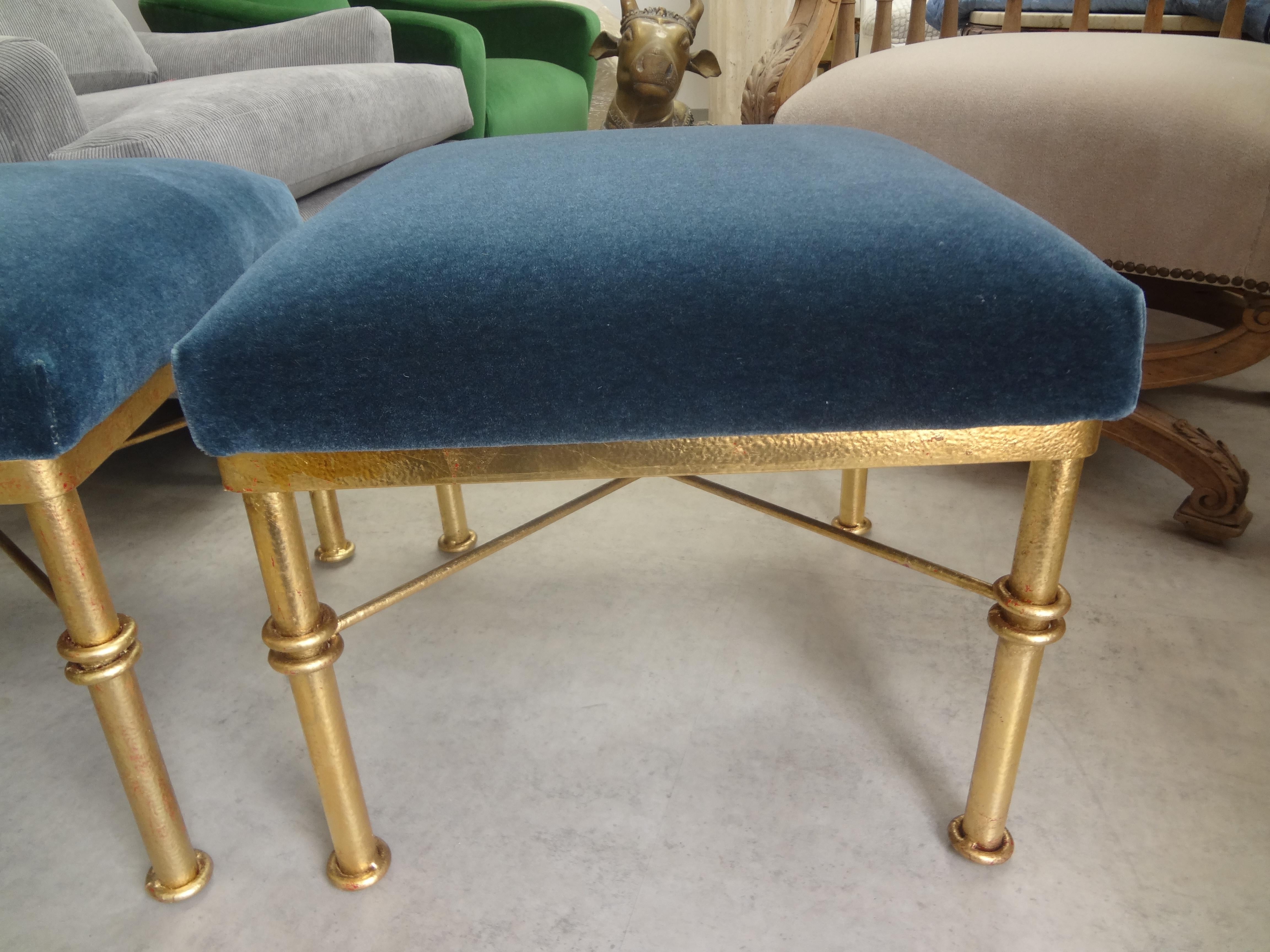 Pair of midcentury gilt iron ottomans. This beautiful pair of gilt ottomans, benches or stools with a knot design were taken down to the frame
and newly upholstered in steel blue mohair. Versatile pair!