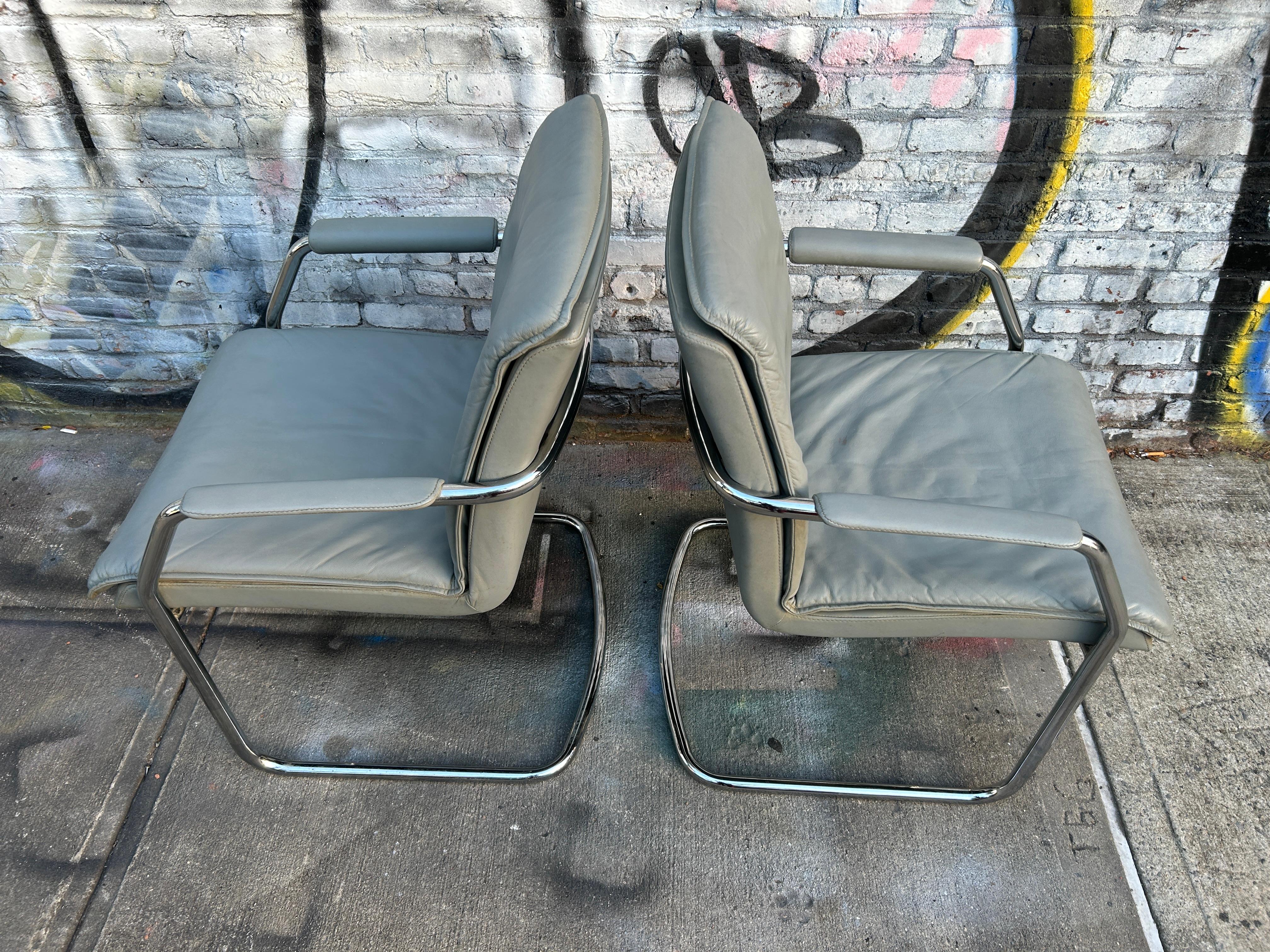 Pair of beautiful cantilevered gray leather lounge or office chairs with chrome tubular frames by Cy Mann. Original super soft gray leather upholstery. Cy Mann is mostly recognized for this chrome lounge chair and other 1970s designs. Labeled under
