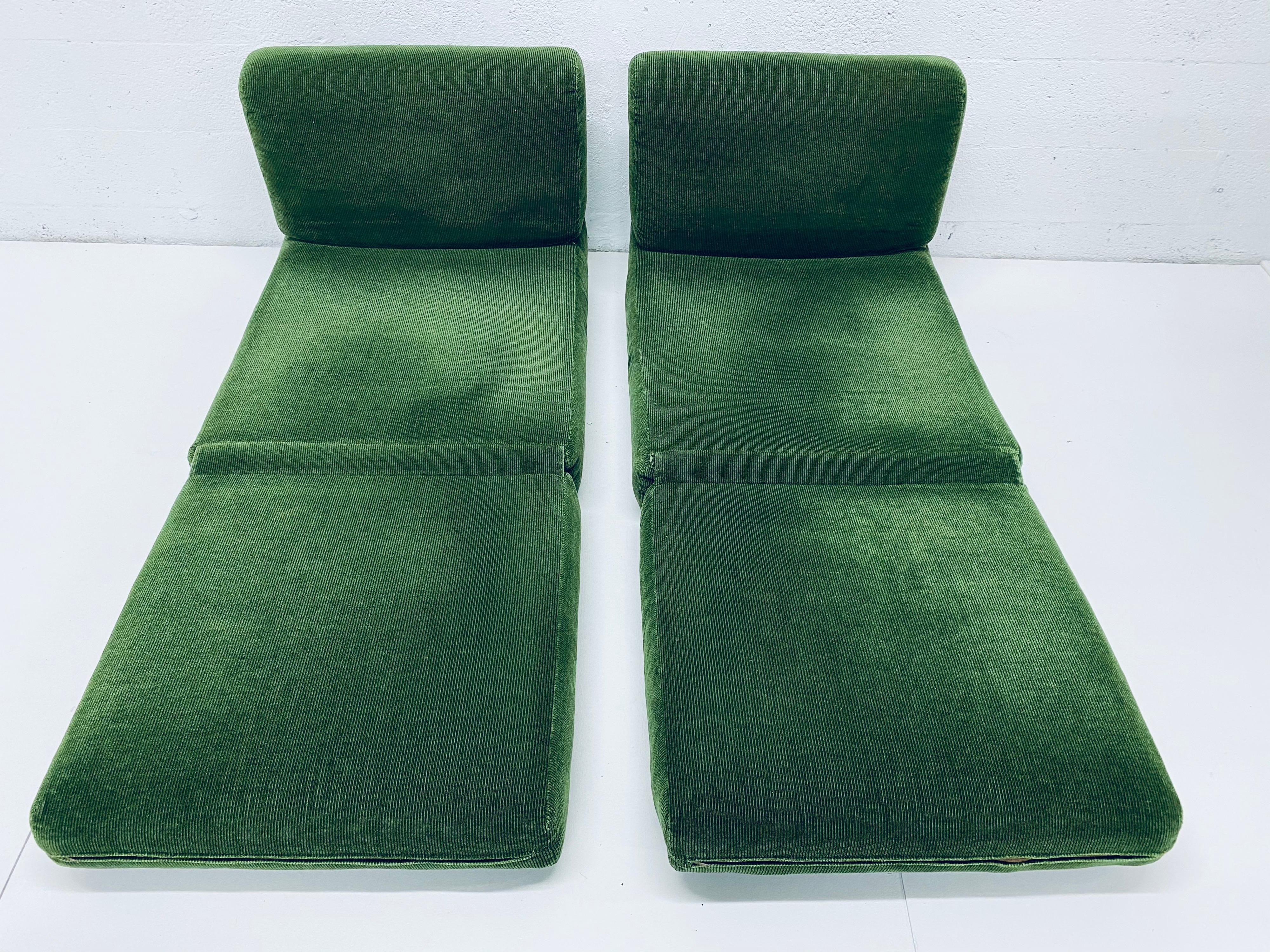 Green corduroy upholstered lounge chairs with pillows that fold out and convert into beds. The chairs are made of a foam back and foam seats. The fabric covers a wood base that the small feet are attached to and keep the chairs off the ground. They