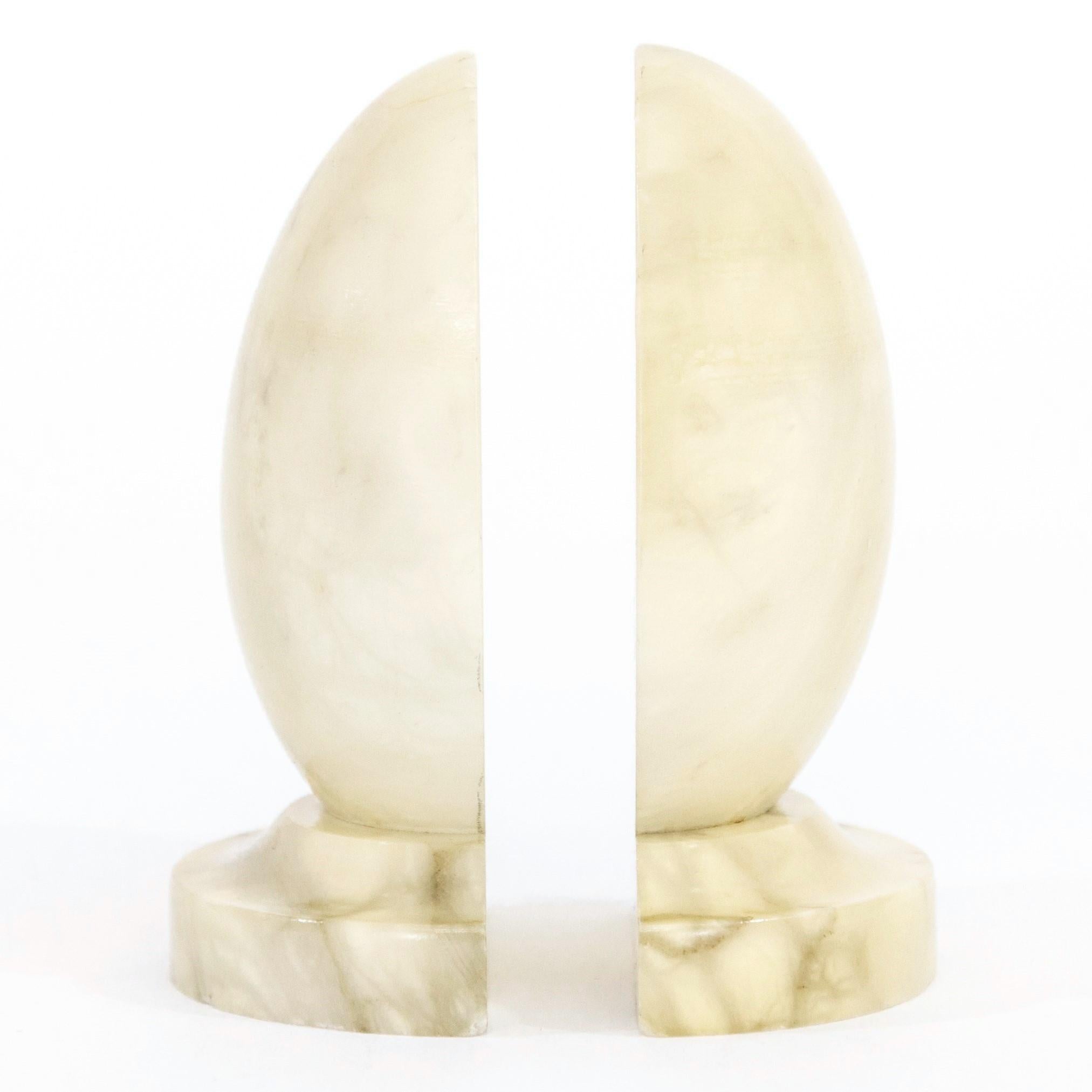 A pair of vintage Italian polished alabaster egg-form bookends, circa 1960s. The natural off-white stone has darkened from age and has gray and tan marbled veining. Each measures 3 7/8